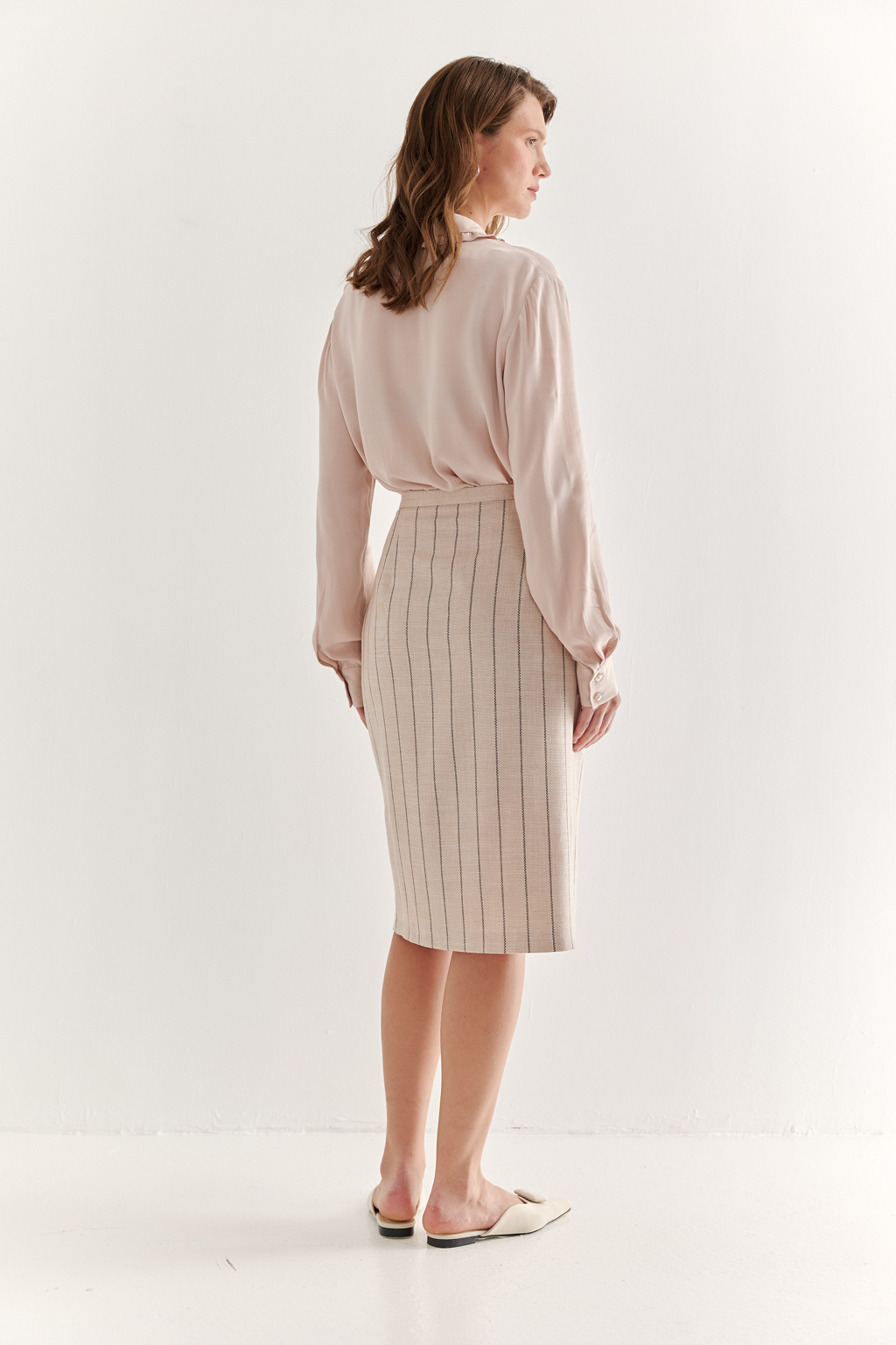 Прямая юбка с запахом выполнена из ткани, представляющей собой уникальную разработку бренда. Сочетание волокон хлопка, вискозы, полиэстера и эластана обеспечивает максимальный комфорт и практичность изделия. Нежный пудрово-розовый оттенок эффектно подчёркнут модной шоколадно-коричневой полоской в широком раппорте. Юбка идеально сочетается с жакетом архитектурного кроя из той же ткани, создавая завершённый формальный образ.