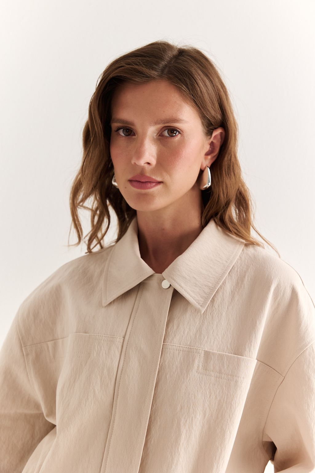 Куртка прямого силуэта длиной до бедер и с кулисой по талии. Воротник рубашечный, застежка под планкой. По полочке накладные карманы-портфели.