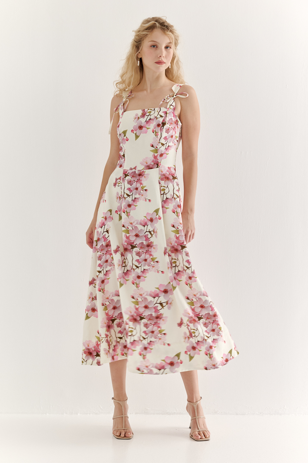 Платье-сарафан полуприлегающего силуэта выполнено из плотной пластичной ткани в основе которой волокна вискозы и льна. Лиф-бандо, акцент на линию талии и юбка полусолнце формируют изящный Х-образный силуэт. Особую утонченность платью придают бретели сложной формы, изящно завязывающиеся на шнуры. Эластичная деталь на спинке платья, собранная на нити-стрейч, и застежка-молния в боковом шве обеспечивают комфортную и превосходную посадку по фигуре. Ключевой деталью, выделяющей этот наряд, является эксклюзивный принт, разработанный в дизайн-бюро бренда. В этом принте нежные розовые цветы сакуры и молочный оттенок фона образуют гармоничное, элегантное сочетание, рождающее ощущение красоты и утонченности.