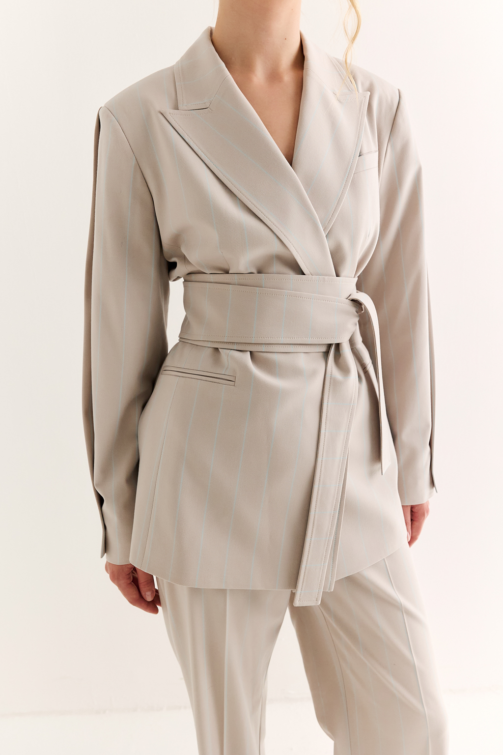 Жакет с поясом-кушаком: мягкая сила и подчёркнутая линия. Этот жакет сочетает в себе структурированную форму и пластичность драпировки. Приталенный силуэт акцентирован широким поясом-кушаком, который завязывается на талии, формируя выразительную линию «песочных часов» и добавляя образу женственности без излишней строгости.
Острые лацканы, аккуратная линия плеч и выверенный крой рукавов делают модель универсальной: для делового дня, кэжуал-комплекта или вечернего выхода. Пояс, завязанный на узел или бант, задаёт настроение и подчеркивает индивидуальность. Гармония формы и мягкости. Жакет, который раскрывает силу через утончённость.