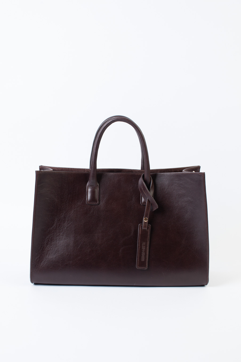 Стильная сумка через плечо глубокого шоколадного оттенка станет незаменимым спутником вашей коллекции. Простая, лаконичная форма идеально впишется в деловой образ. Вместительная модель выполнена из натуральной гладкой кожи с ручками сверху и дополнена ремешком через плечо. Размеры сумки: 39,7*25*14 см.