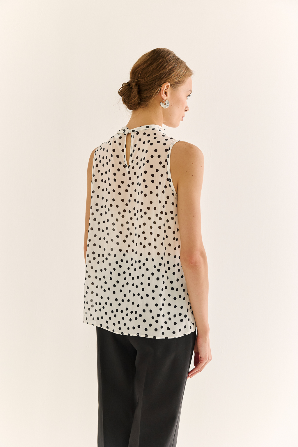 Блузка с бантом: женственность и утончённый акцент. Эта блузка без рукавов — воплощение элегантной простоты с выразительной деталью. Горловина украшена мягким бантом, который добавляет образу нотки утончённости и романтичного шика. Лёгкая драпировка спереди делает силуэт свободным, но изящным, подчёркивая вкус и стиль. Идеальна для офисных будней, деловых встреч или вечерних образов. Эффектно смотрится под жакет или кардиган, но и сама по себе становится акцентом. Сила — в деталях. Женственность — в каждом движении.