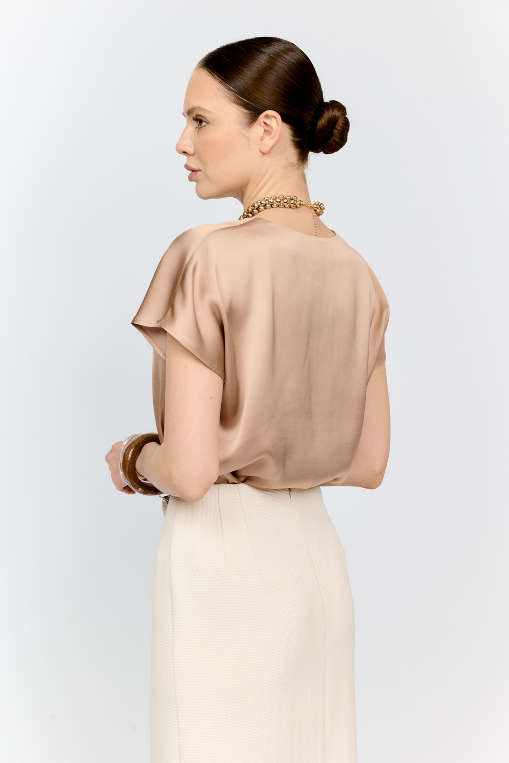 Топ с v-образным вырезом горловины из струящейся и переливающейся вискозы песочного цвета со спущенной линией плеча - отличная база для множества комплектов.