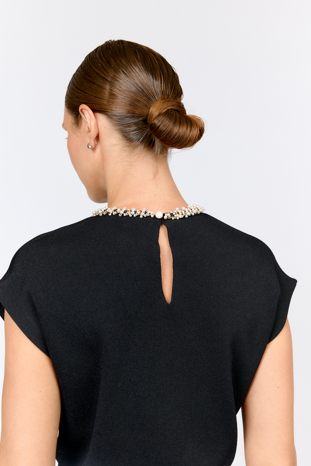 Элегантный топ  с круглой горловиной, декорированной тесьмой. Со спущенным плечом, без рукавов. Свободного силуэта. Изысканная модель из премиального  трикотажа плотной вязки в  молочном цвете. Сбалансированная комбинация вискозы и полиамида  создает комфорт при носке. Материал хорошо держит форму  и не подвержен деформации.  Лаконичный топ с декоративной тесьмой  в универсальном черном цвете  - утонченное решение для вечерних или деловых образов.