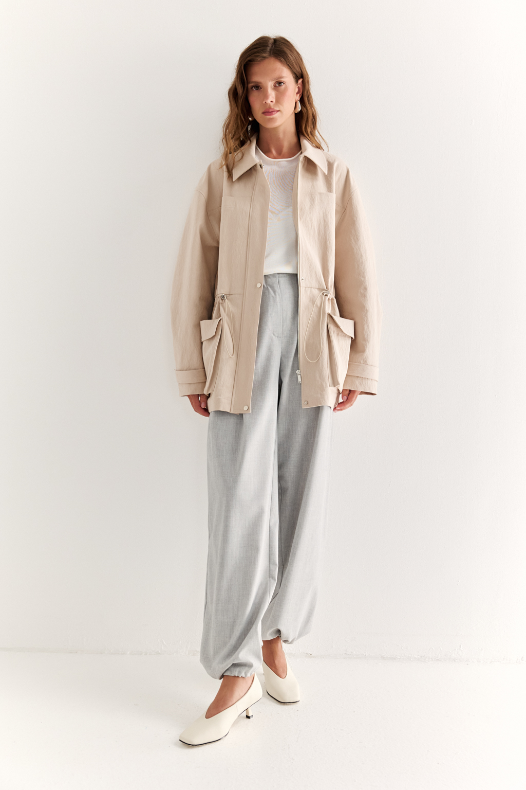 Куртка прямого силуэта длиной до бедер и с кулисой по талии. Воротник рубашечный, застежка под планкой. По полочке накладные карманы-портфели.