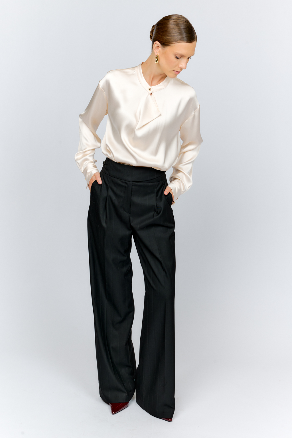 Блуза свободного кроя из шелковистой вискозы с интересной деталью в виде складки на горловине с застежкой на декоративную золотую пуговицу. Изделие придаст стильный акцент к любому образу.