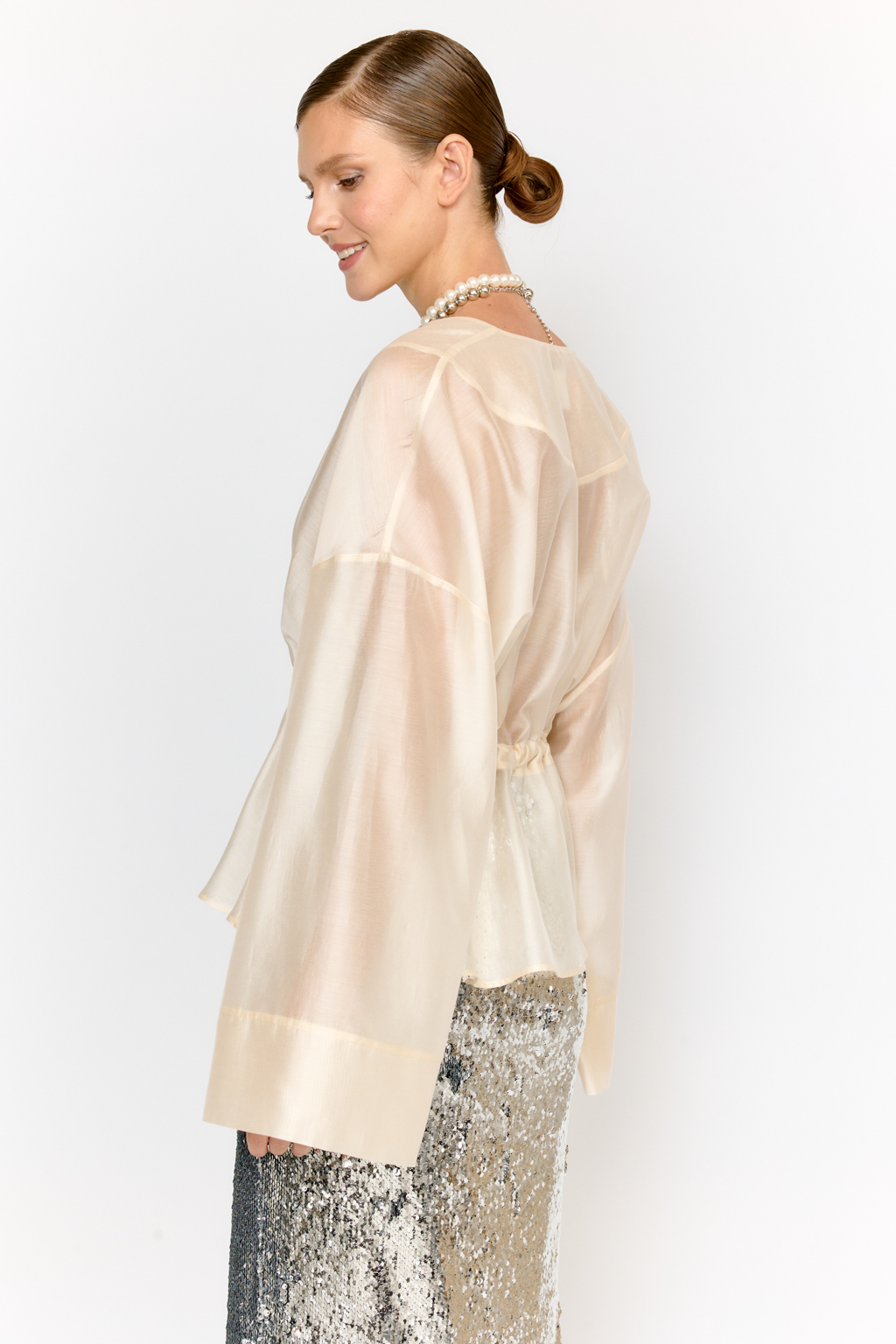 Нарядная блуза из полупрозрачной ткани на кулиске по талии и широкими рукавами большого объема с широкими манжетами по низу дополнит образ с брюками, юбками и платьями в качестве верхнего слоя или в дополнении с топом.  Выполнена из легкой полупрозрачной ткани из тенселя  с содержанием шёлка. Тенсель  -  волокно растительного происхождения, получаемое из древесины эвкалипта по экологически чистому технологическому процессу. Отличается  воздухопроницаемостью и гигроскопичностью.  Шёлк обеспечивает роскошный внешний вид и пластичность ткани.  Преимущества ткани: шелковистая поверхность ткани с жемчужным переливом выглядит премиально и нарядно. Легкая прозрачность делает образ трендовым.