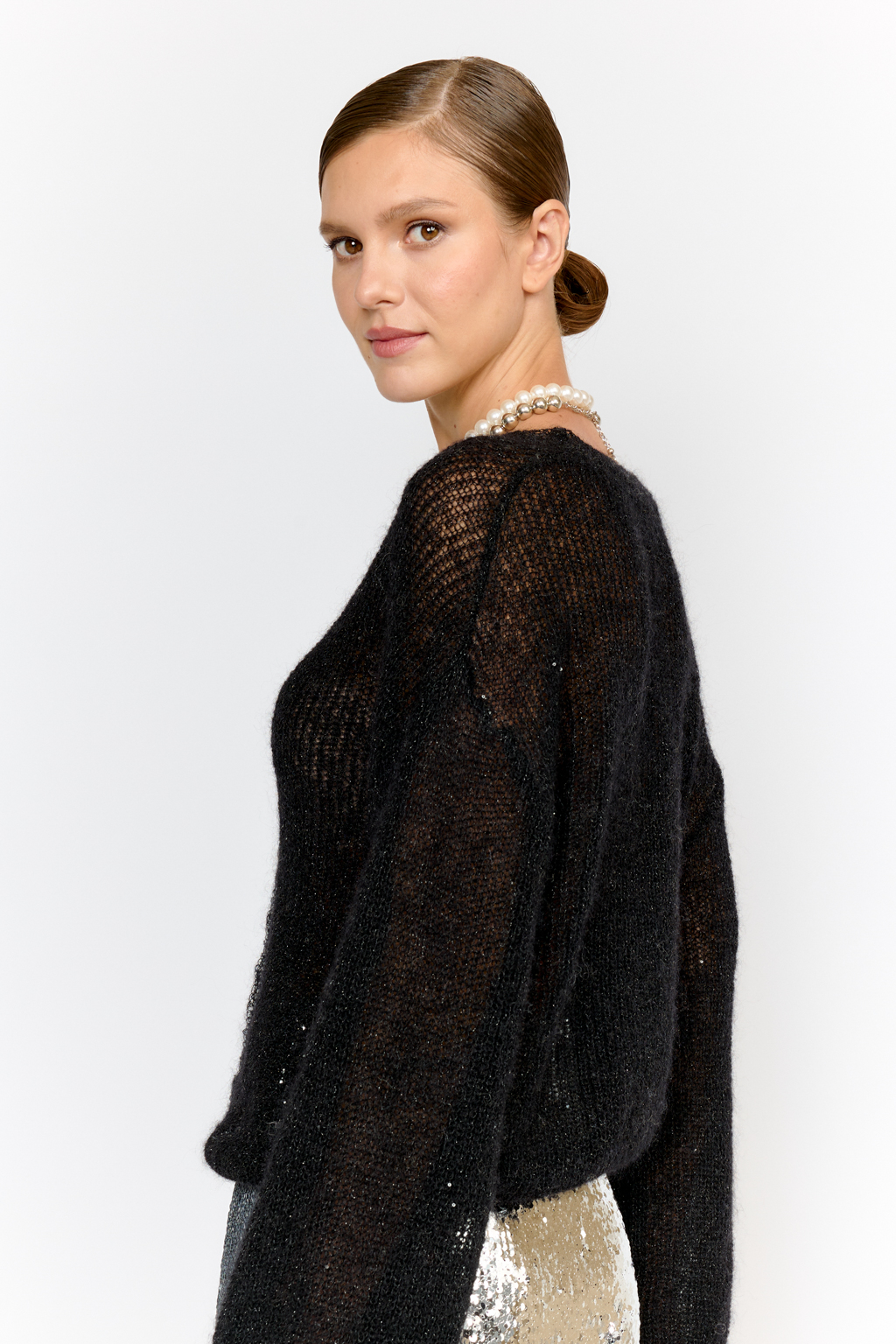 Кардиган с центральной застежкой на пуговицы, V-образной горловиной и длинным рукавом.  Модель свободного силуэта в глубоком черном  оттенке из воздушной пряжи с шерстью и мохером с деликатными мелкими пайетками, придающими легкое сияние. Кардиган очень теплый, несмотря но свою трендовую транспарентность и легкость, благодаря мохеру в составе. Шерсть так же обеспечивает естественную терморегуляцию и уют. Такой кардиган будет выигрышно смотреться в образах с  брюками и юбками из коллекции, а так же дополнит образы с платьями на бретелях или платьем-бандо.