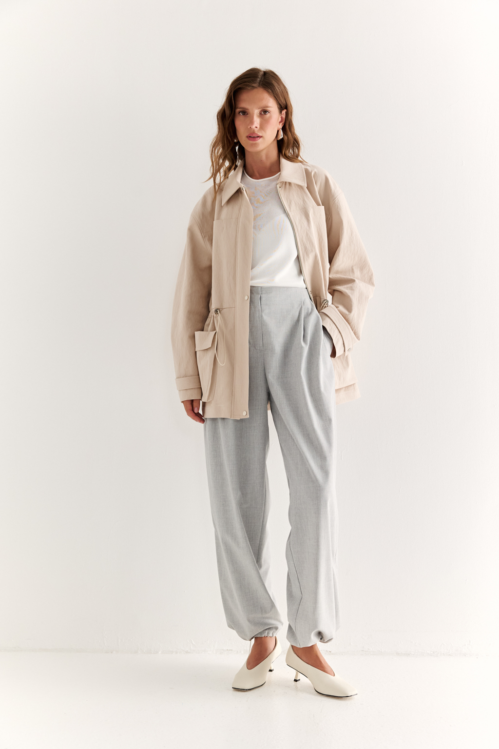 Куртка прямого силуэта длиной до бедер и с кулисой по талии. Воротник рубашечный, застежка под планкой. По полочке накладные карманы-портфели.