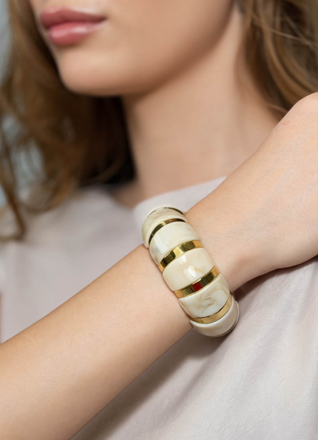 Стильный браслет в бежевом оттенке с золотыми вставками создан для женщин, ценящих неподвластный стиль времени. Изделие выполнено из акрилового ацетата, что обеспечивает его долговечность, легкость и современный дизайн. Крепление на резинке.