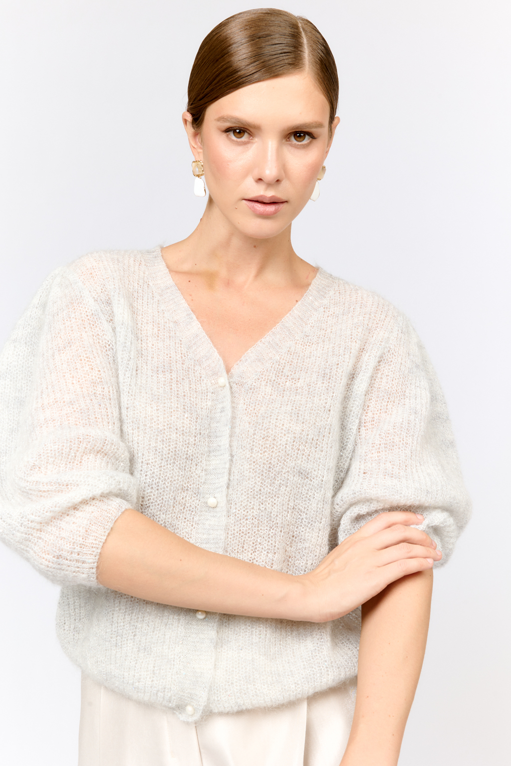 Легкий кардиган с центральной застежкой на пуговицы, V-образной горловиной и укороченным рукавом. Выполнен в премиальной пряже в составе которой, мохер и шерсть. Невесомый на вид, кардиган теплый и уютный. Мохер обладает множеством преимуществ: он легкий, обладает натуральным блеском, прочностью и долговечностью, отлично удерживает тепло. Кроме того, мохер устойчив к скатыванию и деформации. Модель кардигана умеренного объема с укороченным рукавом, идеальна для вечерних образов.