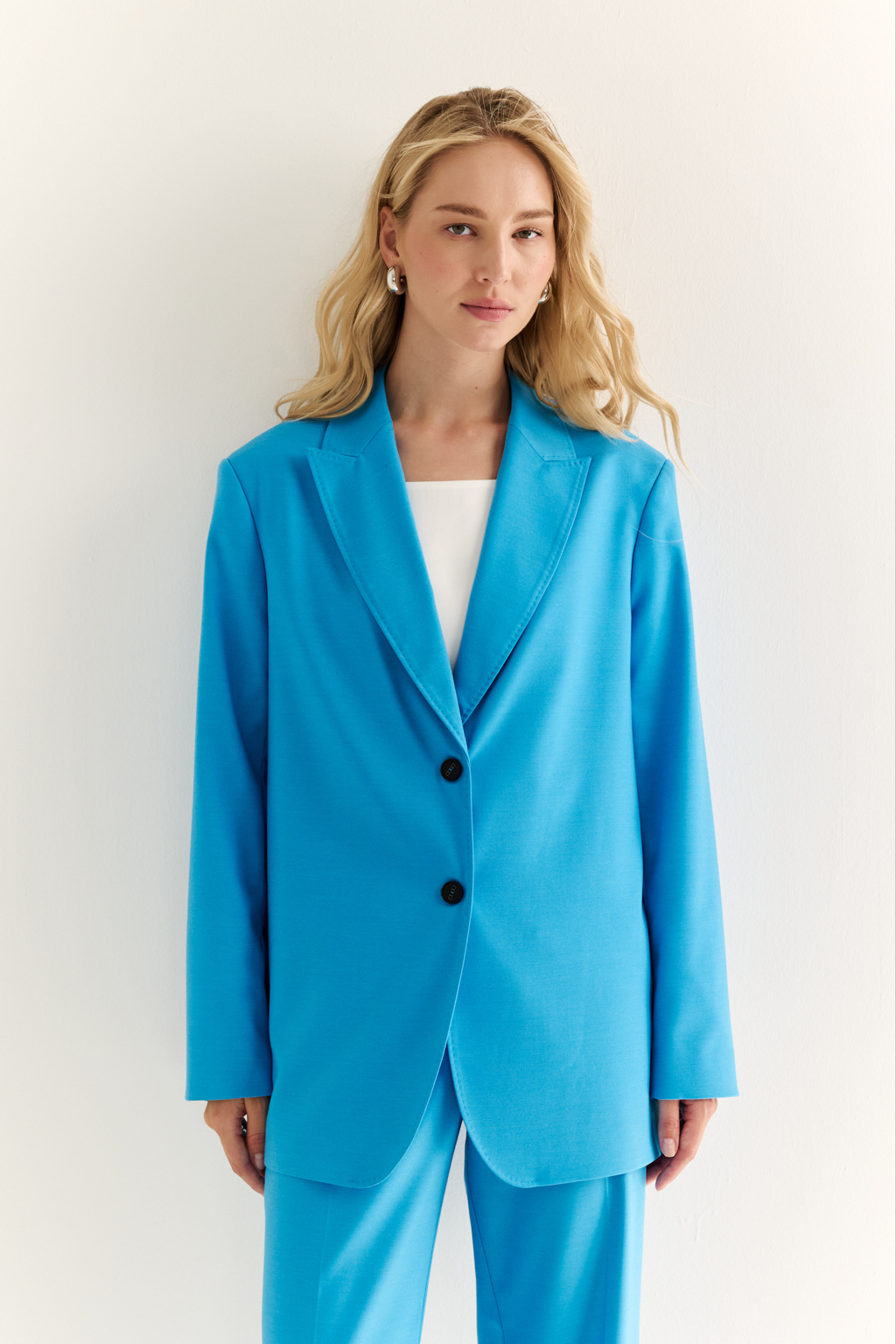 Классический жакет: фундамент уверенного образа. Жакет прямого силуэта с чёткой линией плеч — это безвременная классика, которая подчёркивает вкус и статус. Однобортная застёжка и лаконичные детали делают модель универсальной: она органично впишется как в деловой, так и в повседневный гардероб. Благодаря прямому силуэту и продуманной длине, жакет хорошо садится и визуально стройнит. Идеален в паре с брюками или даже с джинсами — для смелого контраста. Сила в простоте. Элегантность в каждой детали.