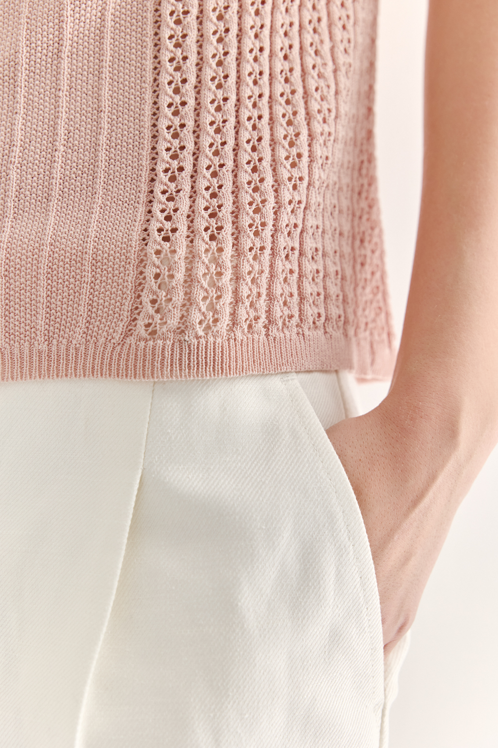 Джемпер-поло нежно-розового цвета полуприлегающего силуэта средней длины из вискозной пряжи, выполнен в комбинации полупрозрачной сетки и жаккарда, низ рукава и оторочка воротника - изящные фестоны. Рукав короткий, застежка на укороченной планке горловины на три пуговицы.