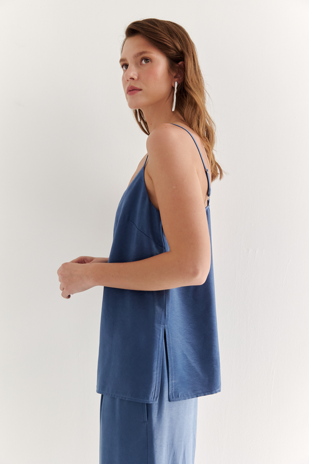 Топ из струящегося атласа с крэш эффектом в цвете деним. Топ на регулируемых бретелях свободного кроя с декором на линии декольте.