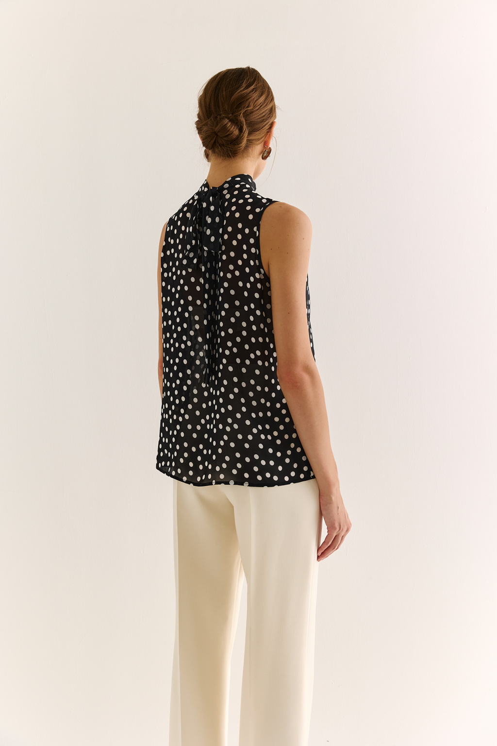 Блузка с бантом: женственность и утончённый акцент. Эта блузка без рукавов — воплощение элегантной простоты с выразительной деталью. Горловина украшена мягким бантом, который добавляет образу нотки утончённости и романтичного шика. Лёгкая драпировка спереди делает силуэт свободным, но изящным, подчёркивая вкус и стиль. Идеальна для офисных будней, деловых встреч или вечерних образов. Эффектно смотрится под жакет или кардиган, но и сама по себе становится акцентом. Сила — в деталях. Женственность — в каждом движении.