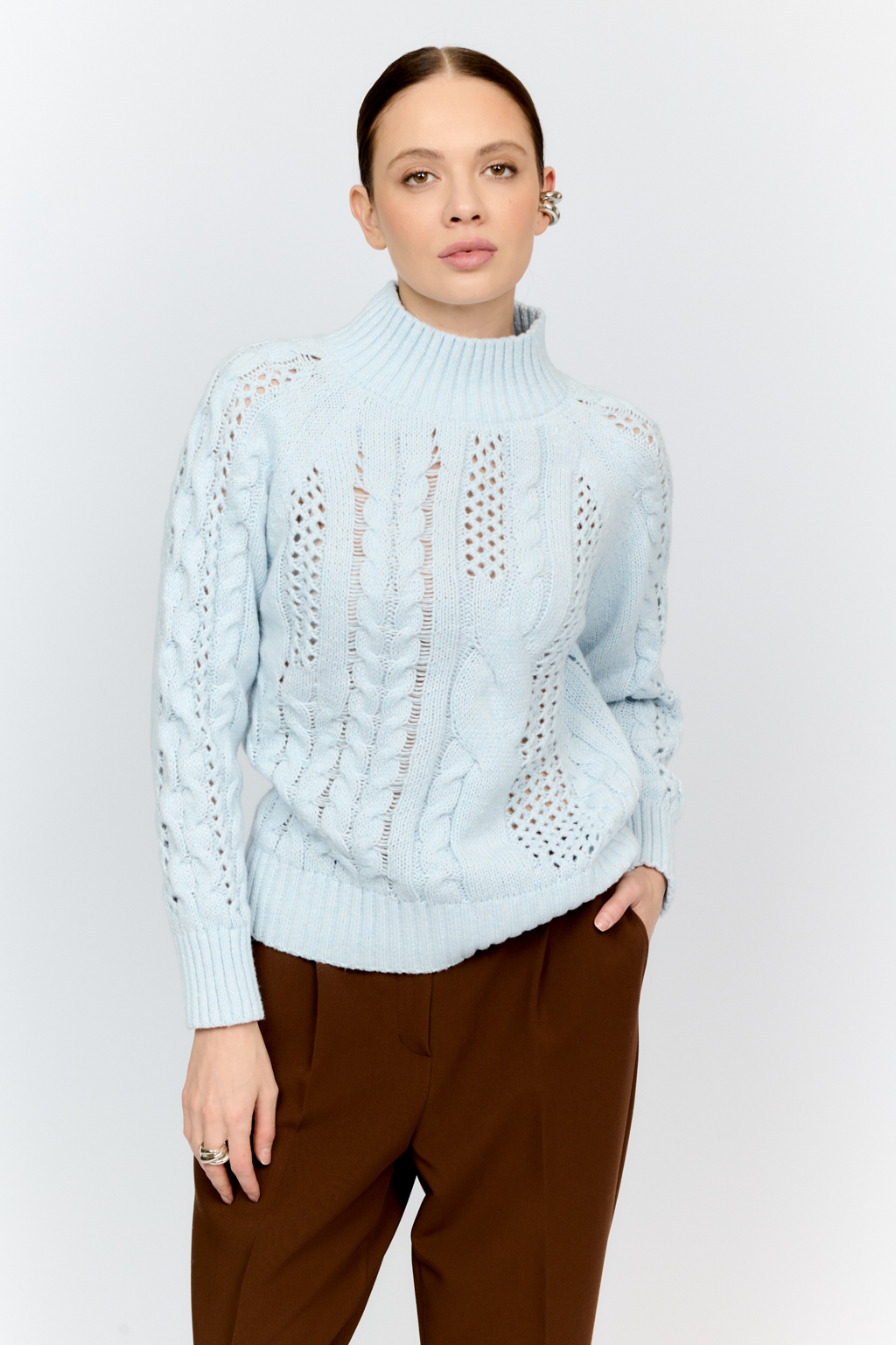 Свитер голубого цвета из мягкой пряжи фигурной вязки с ассиметричными косами, с высокой горловиной и длинным рукавом реглан отлично стилизуется с денимом и обувью на плоском ходу.