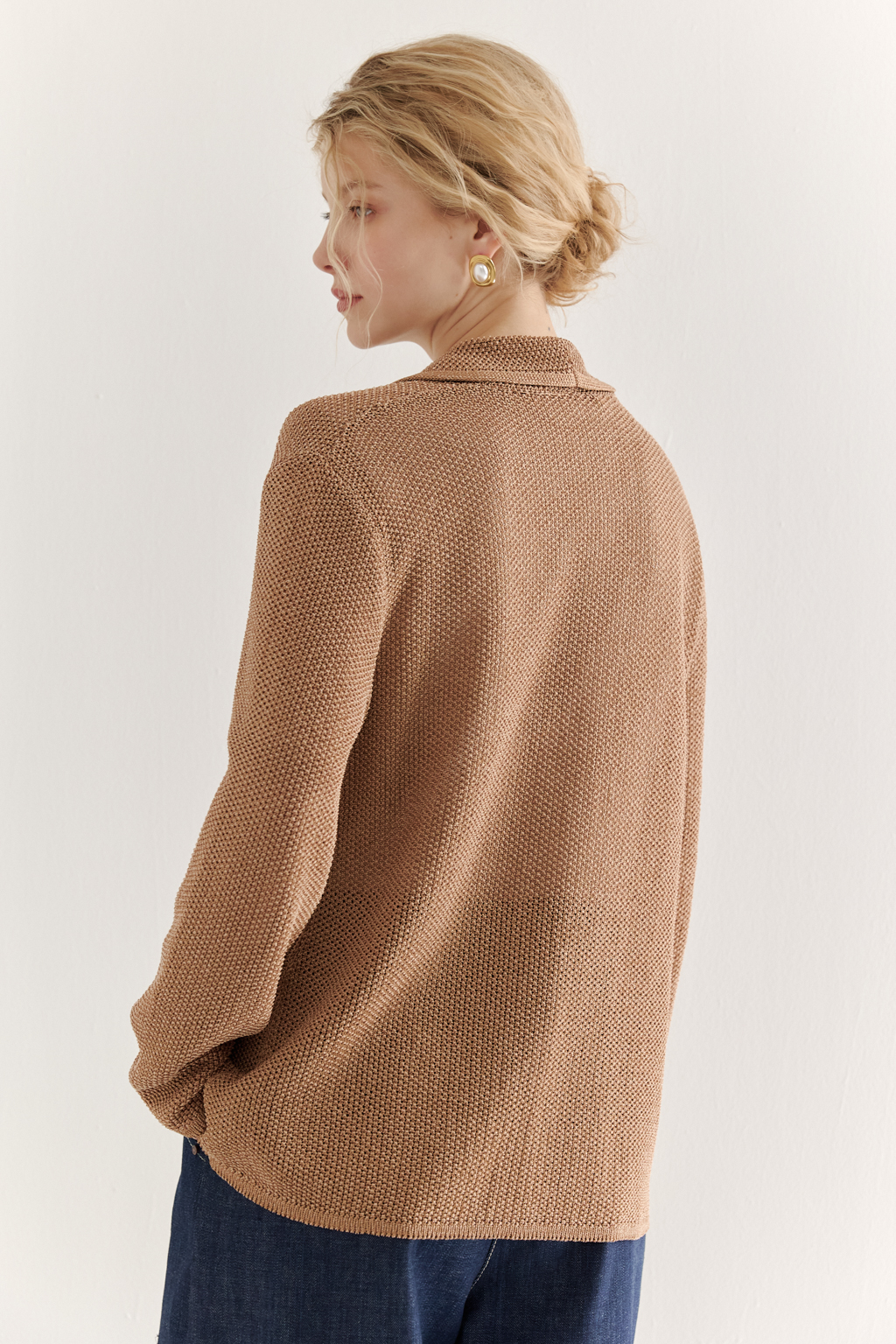 Жакет полуприлегающего силуэта  цвета бронзы из вязанного трикотажа, в составе которого вискоза и хлопок. Плотная скрутка нити образует упругое, но в то же время дышащее полотно. Цельно вязаные лацканы элегантно переходят в воротник, обрамляя вырез. Прямые рукава полной длины завершают лаконичный силуэт. Этот жакет станет изысканным дополнением к непринужденному городскому образу.