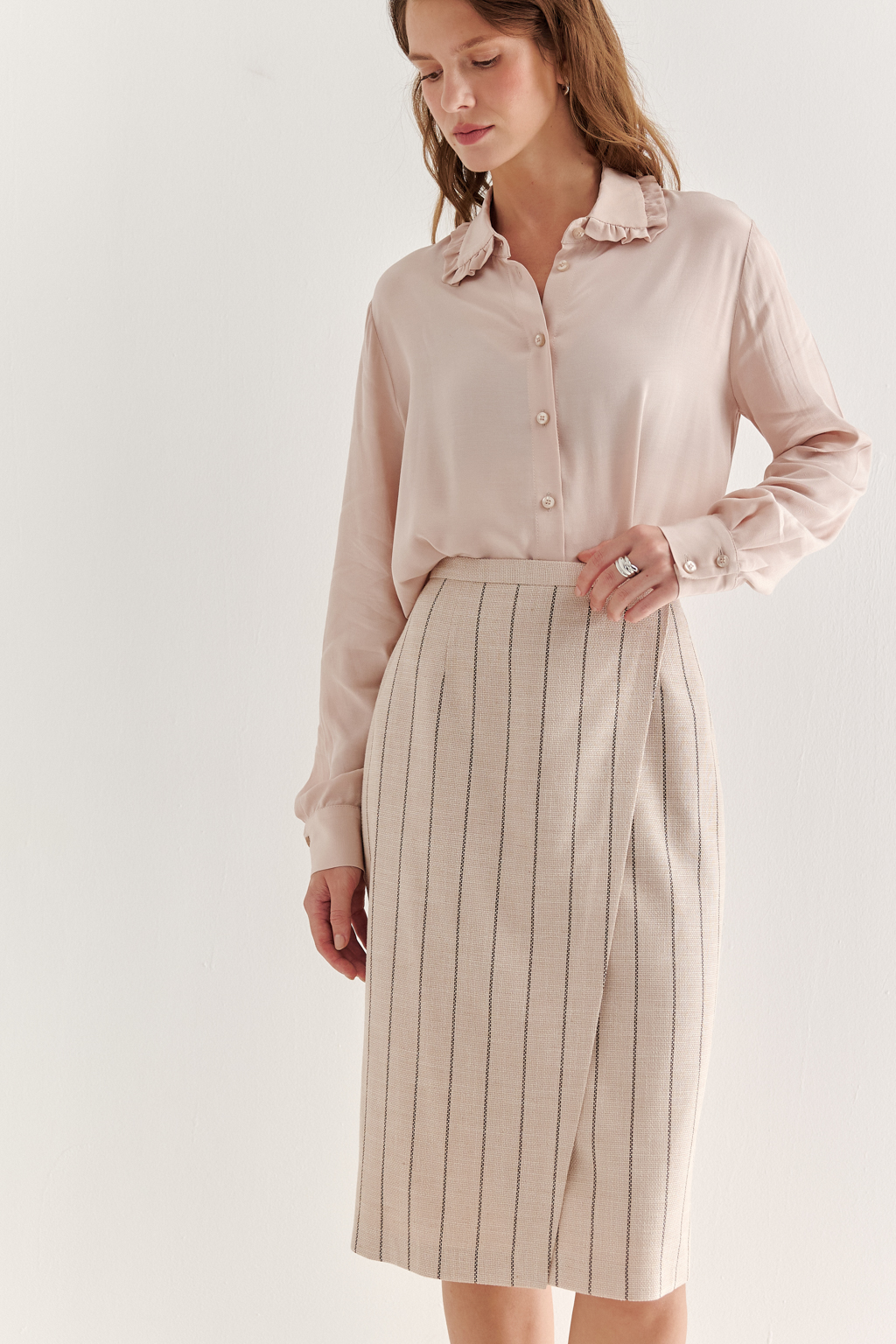 Прямая юбка с запахом выполнена из ткани, представляющей собой уникальную разработку бренда. Сочетание волокон хлопка, вискозы, полиэстера и эластана обеспечивает максимальный комфорт и практичность изделия. Нежный пудрово-розовый оттенок эффектно подчёркнут модной шоколадно-коричневой полоской в широком раппорте. Юбка идеально сочетается с жакетом архитектурного кроя из той же ткани, создавая завершённый формальный образ.