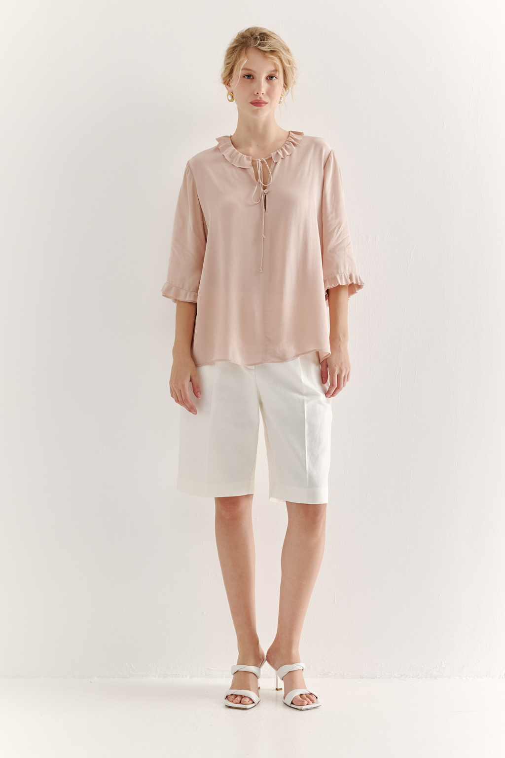 Эта романтичная блуза выполнена из вискозного крепа в нежном пудрово-розовом оттенке. Горловина и рукава украшены изящными рюшами, добавляющими образу легкости и утонченности. Оригинальный разрез спереди кокетливо завязывается на тонкий шнур-рулик и фиксируется воздушной петлей на пуговицу. Прямой силуэт и рукава длиной одна вторая обеспечивают комфорт и свободу движений. Эта блуза — идеальный выбор для создания непринужденных, но элегантных городских образов.