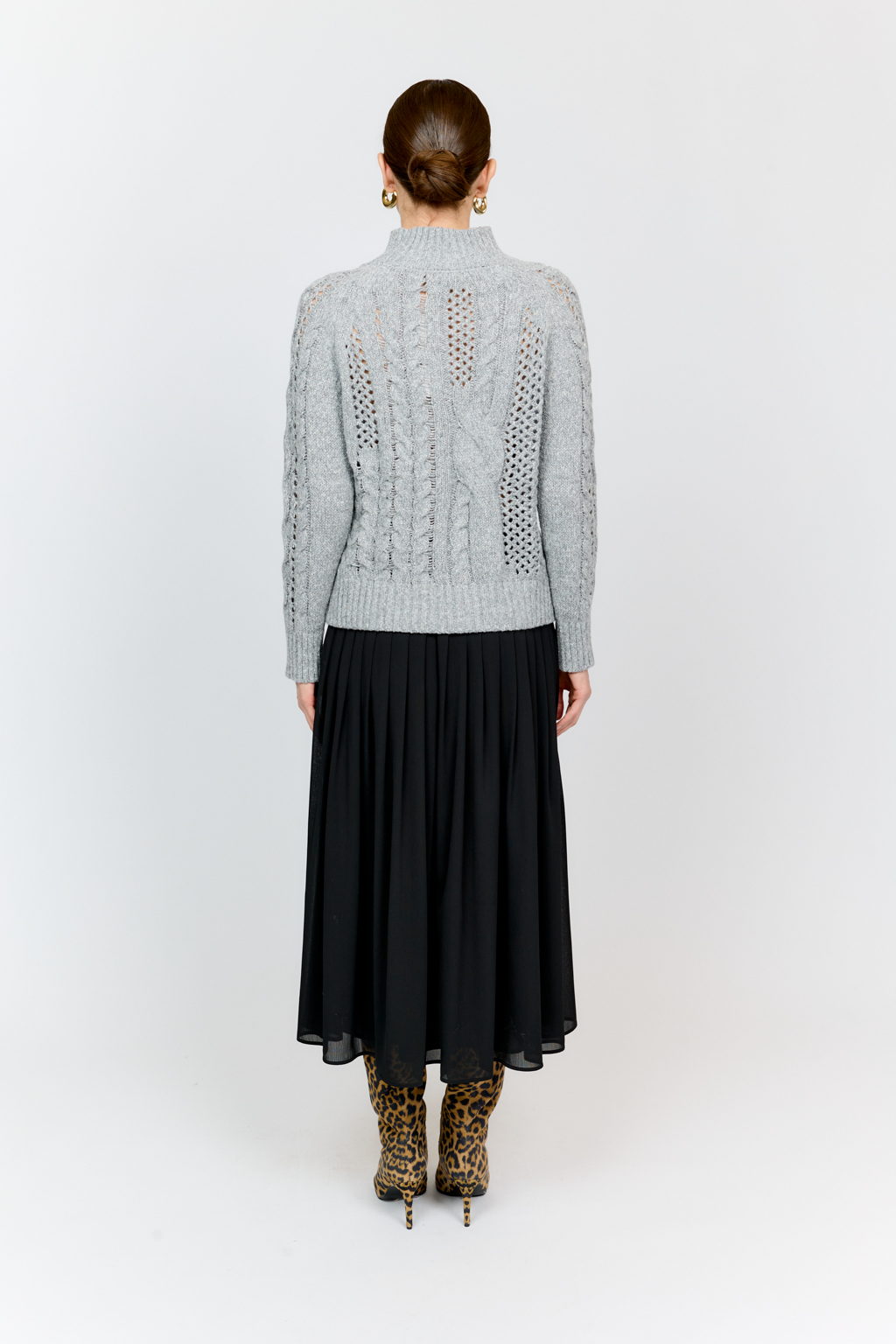 Свитер серого цвета из мягкой пряжи фигурной вязки с ассиметричными косами, с высокой горловиной и длинным рукавом реглан отлично стилизуется с денимом и обувью на плоском ходу.