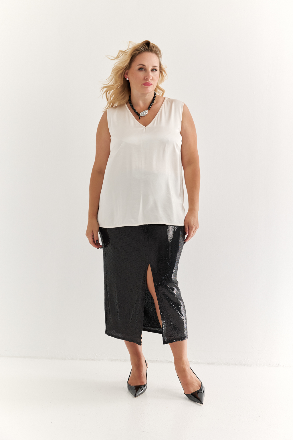 Силуэтная юбка длины миди с разрезом спереди из эластичной ткани с крупными мерцающими пайетками. Полиэстер практичен в уходе, держит форму и устойчив к сминанию. Преимущества ткани: умеренно блестящая, привлекающая  внимание ткань, для создания  эффектных образов. Пайетки придают изделиям уникальный блеск и сияние, делая их запоминающимися и праздничными. Основа  - мягкая пластичная сетка, что делает изделие комфортным.