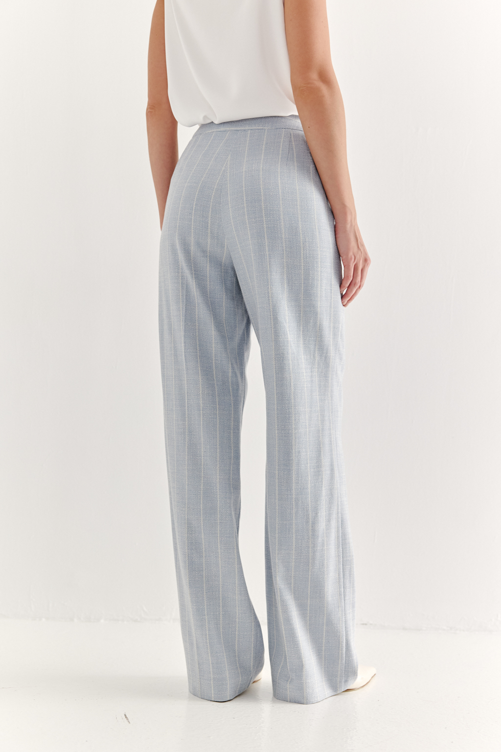 Эти брюки прямого силуэта созданы для абсолютного комфорта и расслабленной элегантности. Выполненные из ткани премиум-класса, они дарят невероятное ощущение мягкости, а нежный небесно-голубой оттенок эффектно подчеркнут светлой полоской в широком раппорте. Средняя посадка и удобные карманы делают их идеальными для любого типа фигуры. Ткань с оригинальным дизайном – эксклюзивная разработка бренда. Состав: хлопок, вискоза, эластан; за долговечность отвечает полиэстер. Брюки идеально дополнят городской look с жакетом архитектурного кроя их этой же ткани, создавая модный многослойный образ.