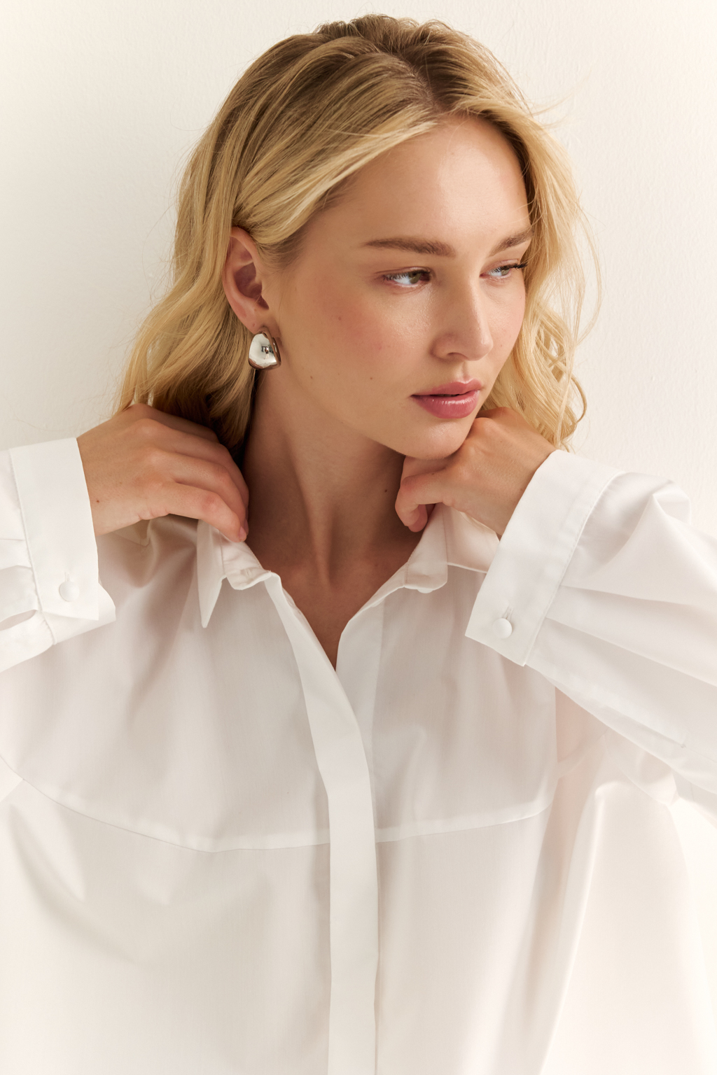 Oversize-рубашка с кокеткой: объём как способ выразить себя. Эта укороченная рубашка с удлинённой кокеткой и объёмными рукавами — модный акцент, который задаёт ритм всему образу. Мягко закруглённый низ подчёркивает талию и визуально вытягивает силуэт, а объёмный крой создаёт эффект расслабленного шика. Широкая кокетка, фактурные швы и сборка по рукавам добавляют архитектурности и свежести классической рубашке. Застёжка на пуговицы и аккуратный воротник сохраняют баланс между формальностью и актуальностью. Новая форма свободы — уверенная, воздушная, выразительная.
