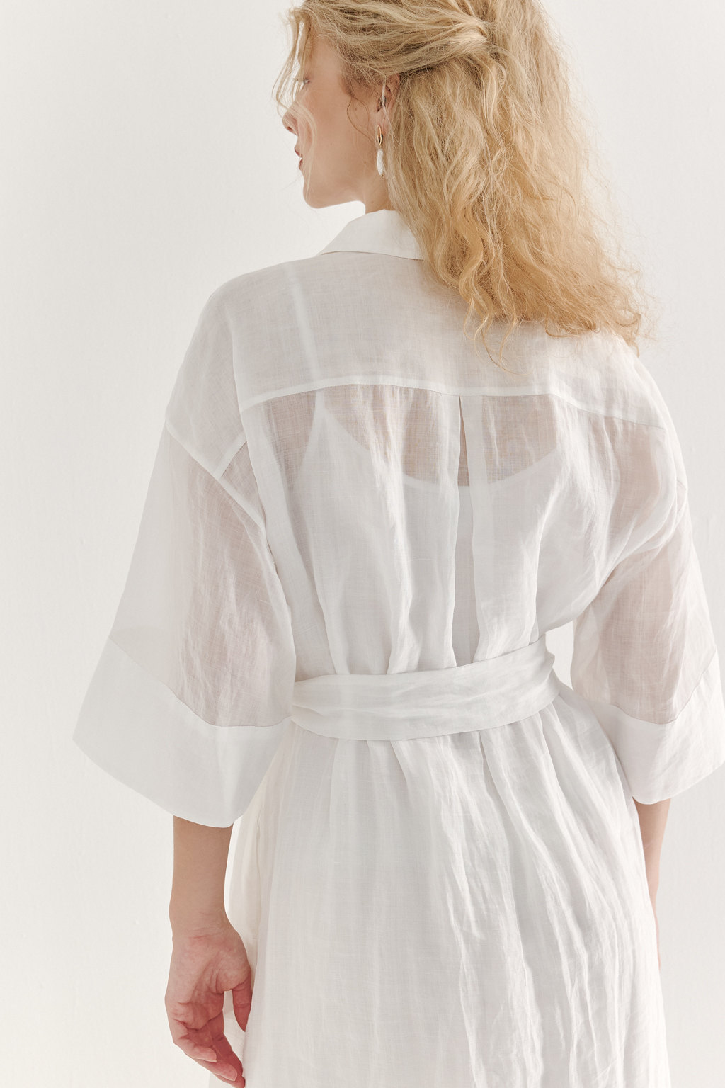Это комфортное платье – традиционный образ для жаркого летнего дня. Платье изготовлено из воздушной невесомой вуали молочного цвета, в составе которой комфортный и экологичный материал крапива. Отложной воротник, планка для застежки, кокетка спинки, втачной широкий рукав одна вторая с отворотом, притачной бордюр по низу платья, пояс-самовяз и трапецивидный силуэт создают максимально комфортное образ. Возможно создание естственного крэш-эффекта, платье не требует сложного ухода.