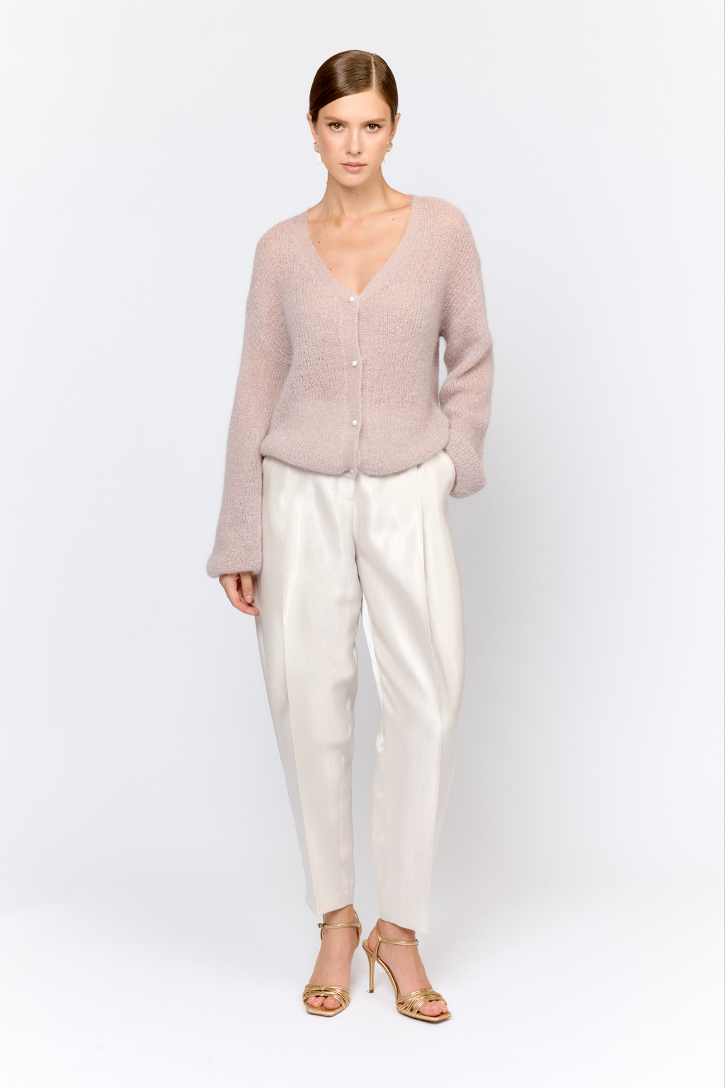 Кардиган с центральной застежкой на пуговицы, V-образной горловиной и длинным рукавом. Модель свободного силуэта в нежном пудровом оттенке из воздушной пряжи с шерстью и мохером с деликатными мелкими пайетками, придающими легкое сияние. Кардиган очень теплый, несмотря на свою трендовую транспарентность и легкость, благодаря мохеру в составе. Шерсть так же обеспечивает естественную терморегуляцию и уют. Такой кардиган будет выигрышно смотреться в образах с брюками и юбками из коллекции, а так же дополнит образы с платьями на бретелях или платьем-бандо.