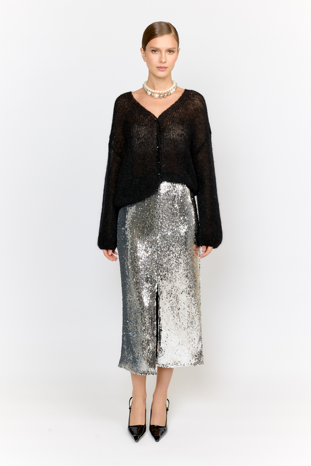 Кардиган с центральной застежкой на пуговицы, V-образной горловиной и длинным рукавом.  Модель свободного силуэта в глубоком черном  оттенке из воздушной пряжи с шерстью и мохером с деликатными мелкими пайетками, придающими легкое сияние. Кардиган очень теплый, несмотря но свою трендовую транспарентность и легкость, благодаря мохеру в составе. Шерсть так же обеспечивает естественную терморегуляцию и уют. Такой кардиган будет выигрышно смотреться в образах с  брюками и юбками из коллекции, а так же дополнит образы с платьями на бретелях или платьем-бандо.