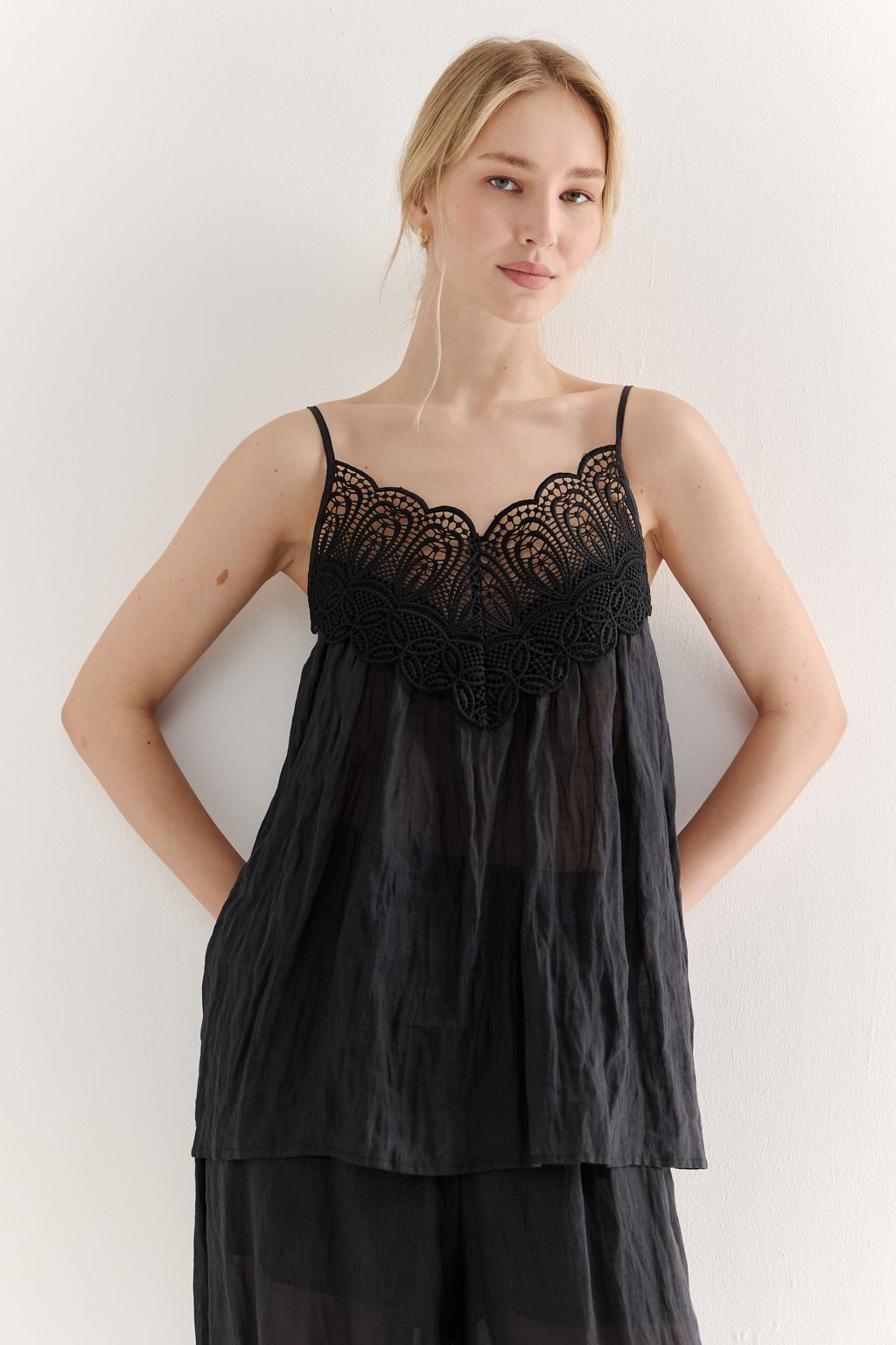 Топ-трапеция, выполненный из стопроцентной крапивы с крэш эффектом в черном цвете, украшен отделкой из кружевного гипюра в тон основной ткани. Кружевная деталь изысканно располагается на передней части изделия. Деталь переда топа настрочены на кружево со сборкой, по верхнему срезу спинки предусмотрена резинка, обеспечивающая оптимальную посадку. Бретели топа регулируются. Топ представляет собой идеальный комплект с брюками из крапивы, льна или хлопка, создавая гармоничный и стильный образ. Хранить в свернутом состоянии.