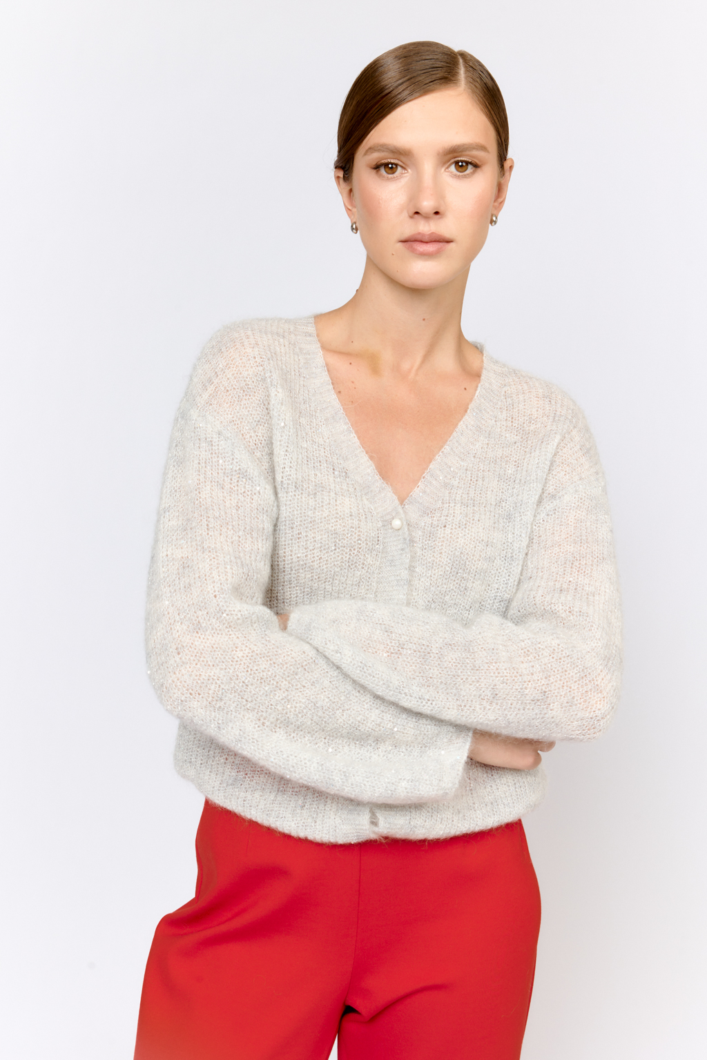 Кардиган с центральной застежкой на пуговицы, V-образной горловиной и длинным рукавом.  Модель свободного силуэта в жемчужно-сером  оттенке из воздушной пряжи с шерстью и мохером с деликатными мелкими пайетками, придающими легкое сияние. Кардиган очень теплый, несмотря но свою трендовую транспарентность и легкость, благодаря мохеру в составе. Шерсть так же обеспечивает естественную терморегуляцию и уют. Такой кардиган будет выигрышно смотреться в образах с  брюками и юбками из коллекции, а так же дополнит образы с платьями на бретелях или платьем-бандо.