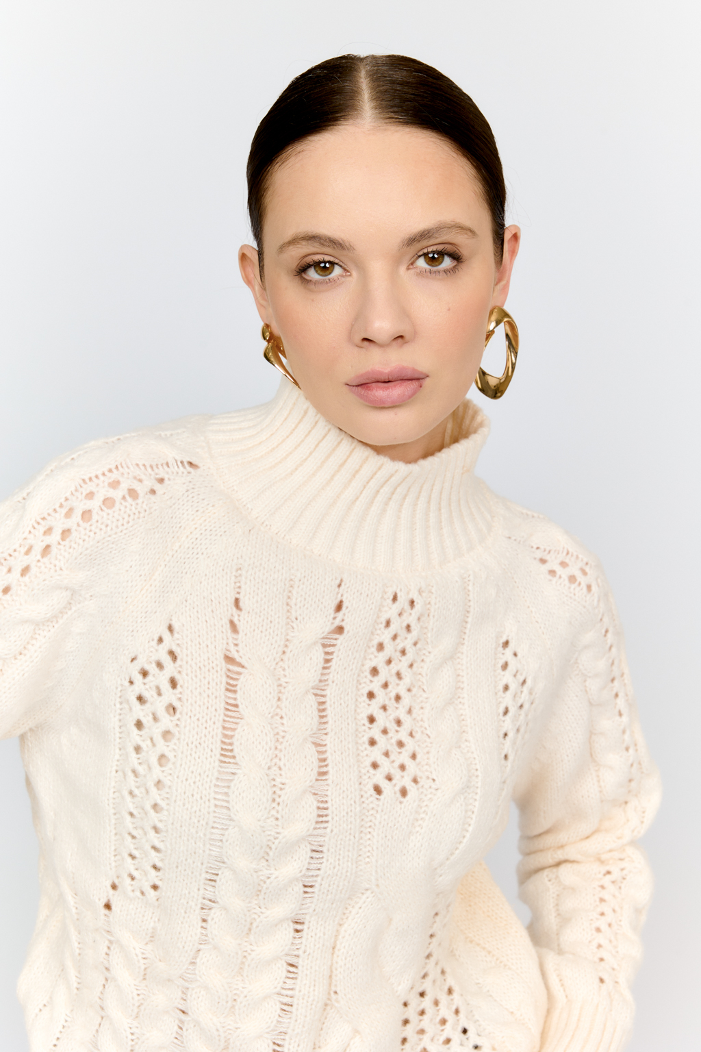 Свитер молочного цвета из мягкой пряжи фигурной вязки с ассиметричными косами, с высокой горловиной и длинным рукавом реглан отлично стилизуется с денимом и обувью на плоском ходу.