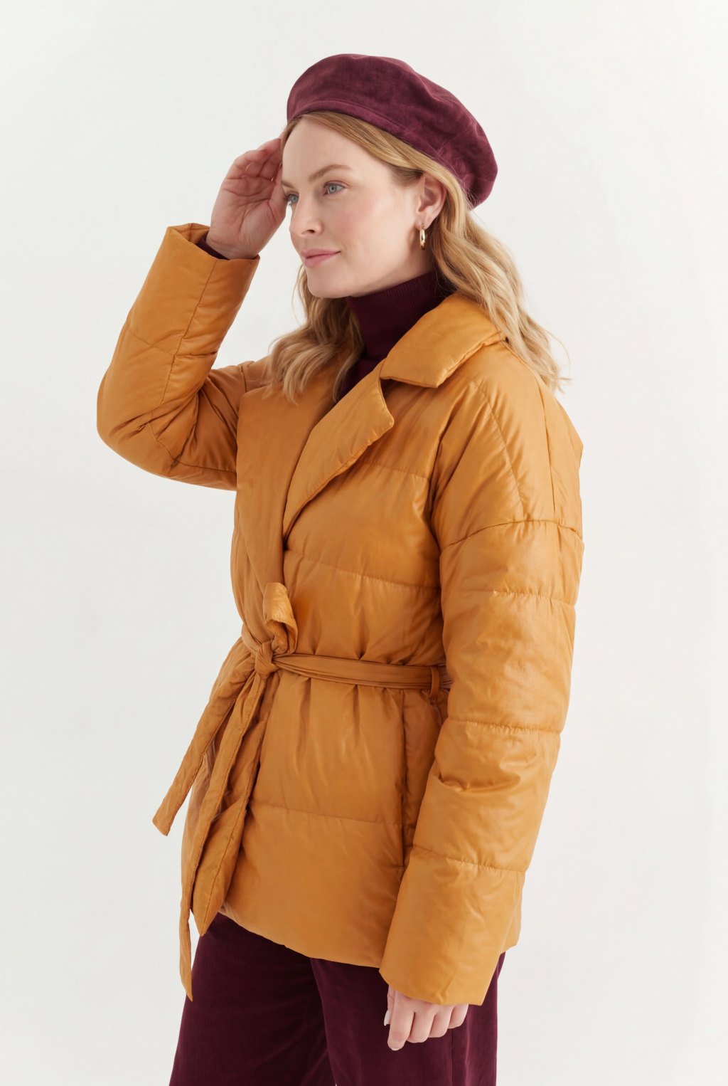 Короткий стеганый пуховик с английским воротником в горчичном цвете, застегивается на кнопки, имеет регулируемый пояс, что позволяет носить изделие в разных вариациях.