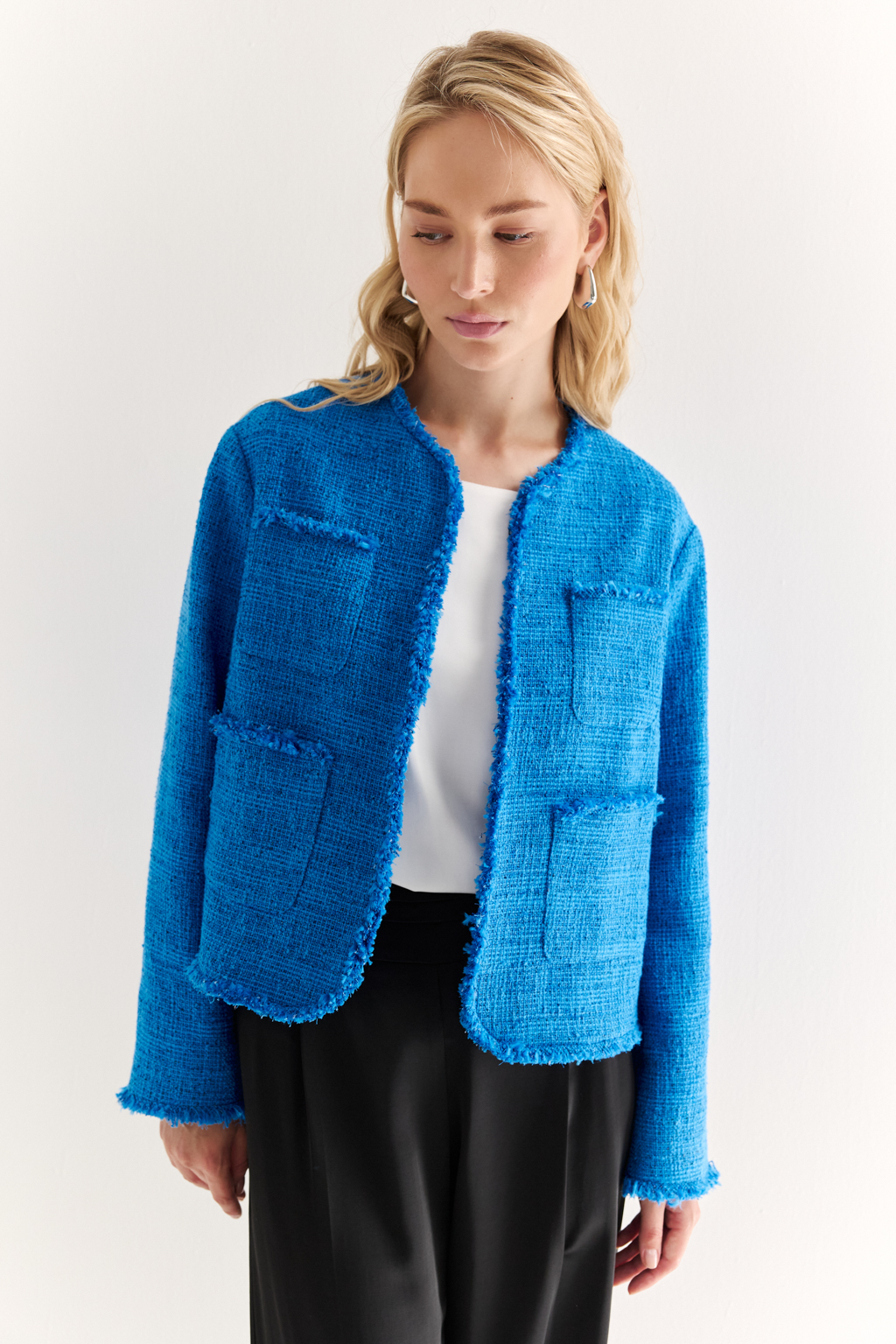 Жакет в стиле Chanel: текстура, изящество, характер
Икона стиля в современной интерпретации — укороченный жакет с застёжкой на крючки и декоративной бахромой по краям. Круглый вырез, слегка расклешенный силуэт и акцентные накладные карманы формируют элегантную геометрию, а текстурная отделка добавляет образу артистичной дерзости.
Эта модель легко становится центральным элементом образа — носите с юбкой, брюками или даже джинсами, создавая контраст между фактурой и формой. Идеальный выбор для женственного, но уверенного стиля.
Современная классика с французским акцентом.