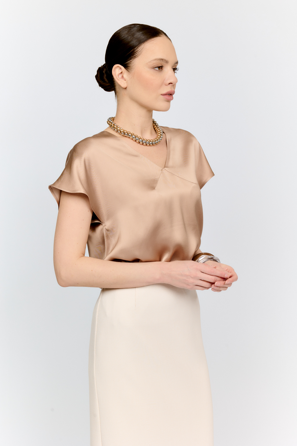 Топ с v-образным вырезом горловины из струящейся и переливающейся вискозы песочного цвета со спущенной линией плеча - отличная база для множества комплектов.