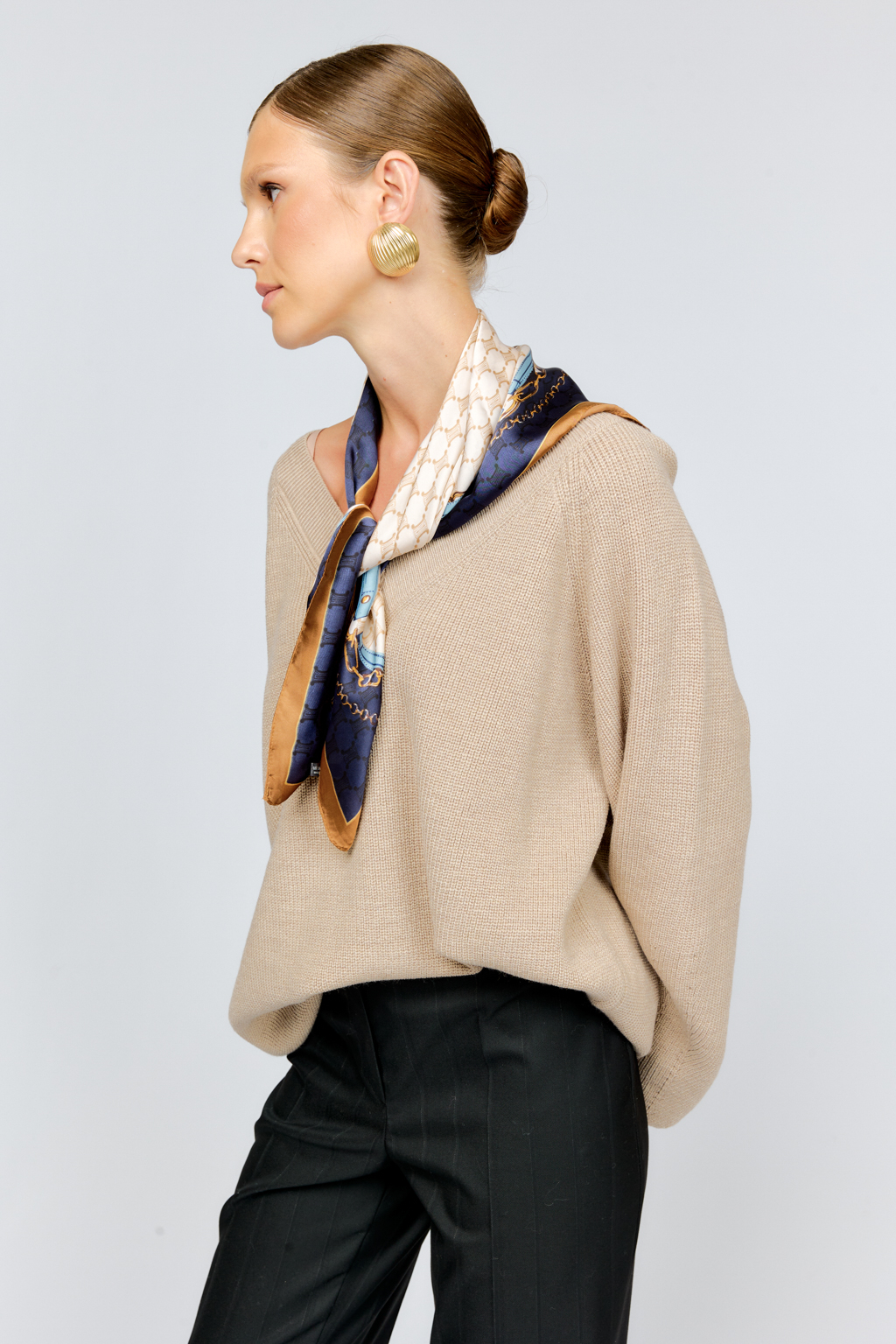 Трикотажный джемпер бежевого цвета свободного силуэта с V-образным вырезом горловины и рукавами реглан из шерстяной смесовой пряжи станет центром комфортных осенних образов.