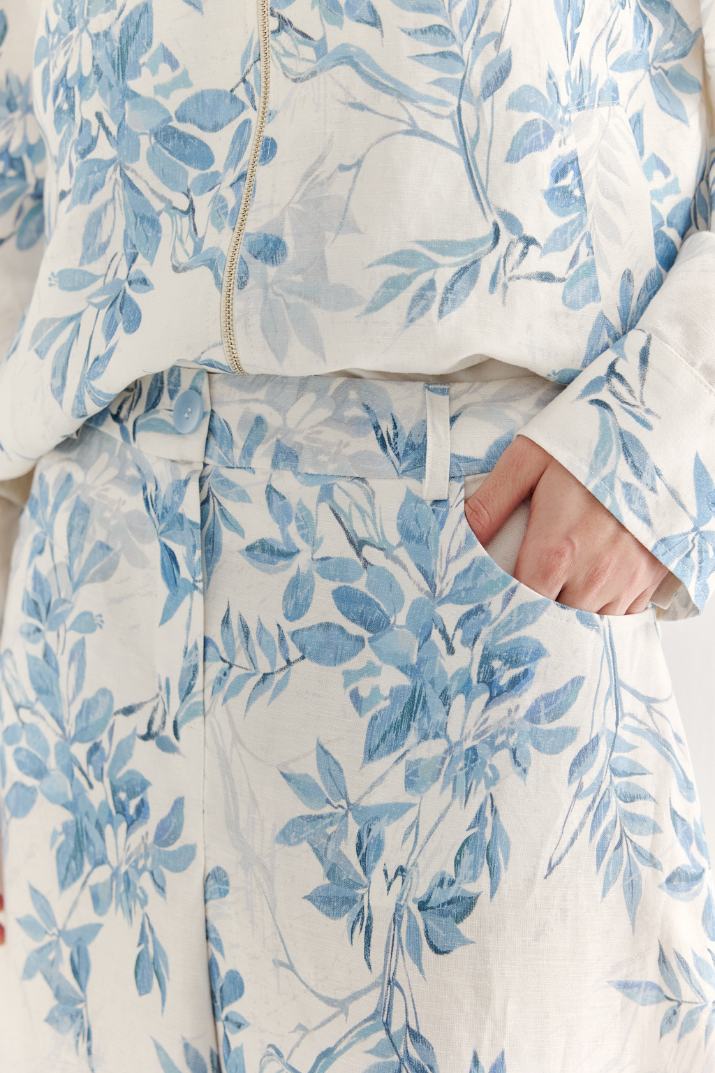 Юбка А-силуэта выполнена из ткани, в составе которой лен и вискоза. Классические детали, такие как пояс, шлевки, гульфик, кокетка спинки и отстроченные швы, представляют собой традиционное решение для джинсовых коллекций. Изюминкой модели является глубокая складка по переднему шву, обеспечивающая дополнительный комфорт и свободу движений. Главный акцент – принт в стиле знаменитого одноцветного Туаль де Жуи, где диагональная композиция из листьев и цветов выполнена в голубом цвете.