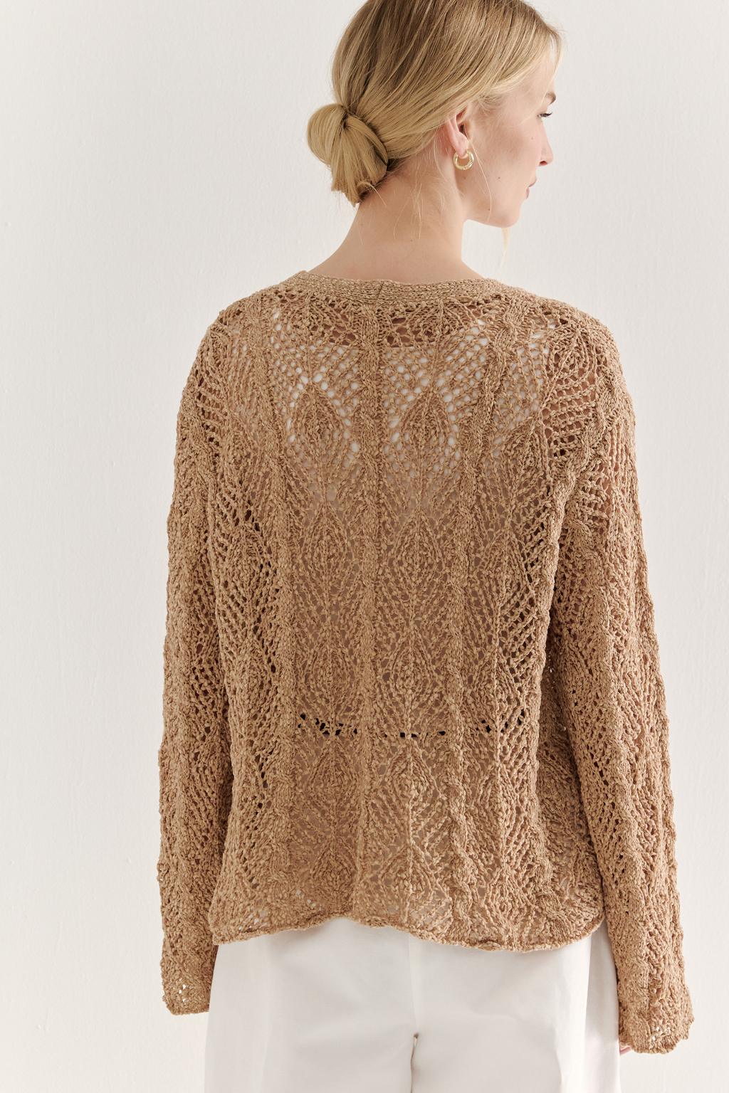 Бежевый вязаный кардиган оверсайз силуэта из хлопковой пряжи. Кардиган связан в сложной технике комбинирования сетки и ажурных ромбов. Рукав прямой удлиненный, V-образный вырез, борт отделан планкой, застежка по борту на 3 пуговицы, низ кардигана и рукав – сложные фестоны.