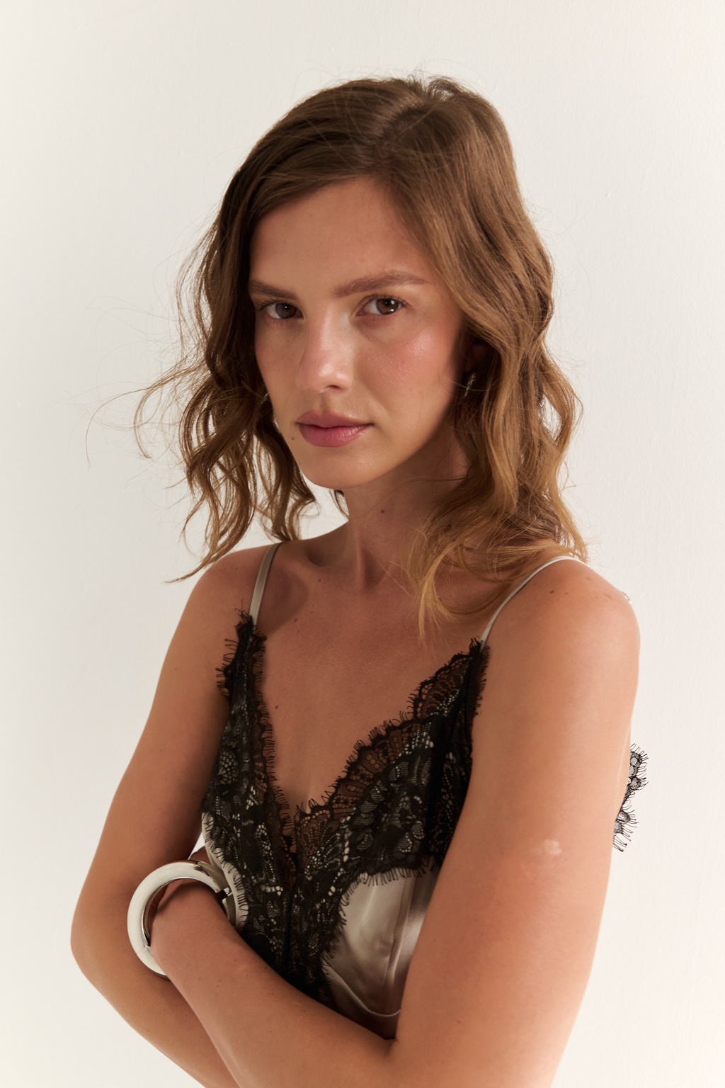 Топ-майка на тонких бретелях отделанный декоративным кружевом по линии горловины и низа. Скроен по косой.  Идеальный вариант под жакеты и трикотажные кардиганы. Вискоза придает ткани мягкость, пластичность и легкий благородный блеск. Район обеспечивает струящуюся фактуру и комфорт в носке. Преимущества ткани: деликатный матовый перелив, создающий утонченный акцент на контрасте с кружевом. Ткань хорошо драпируется, формируя мягкие и чистые линии силуэта. Натуральная основа обеспечивает комфорт.