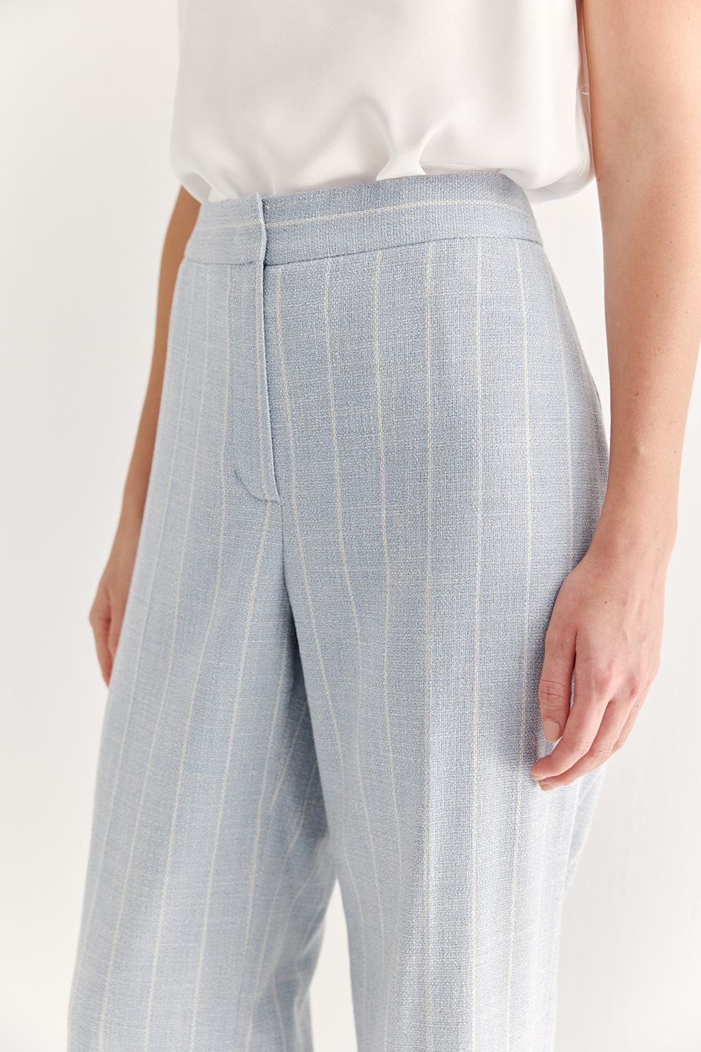 Эти брюки прямого силуэта созданы для абсолютного комфорта и расслабленной элегантности. Выполненные из ткани премиум-класса, они дарят невероятное ощущение мягкости, а нежный небесно-голубой оттенок эффектно подчеркнут светлой полоской в широком раппорте. Средняя посадка и удобные карманы делают их идеальными для любого типа фигуры. Ткань с оригинальным дизайном – эксклюзивная разработка бренда. Состав: хлопок, вискоза, эластан; за долговечность отвечает полиэстер. Брюки идеально дополнят городской look с жакетом архитектурного кроя их этой же ткани, создавая модный многослойный образ.