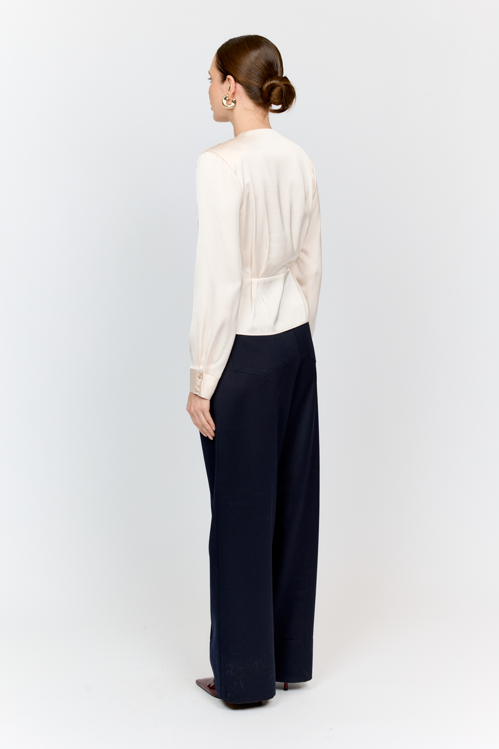 Блуза с глубоким V-образным вырезом горловины и фигурным резом по линией груди, на которой заложены глубокие складки из вискозы с атласной фактурой.