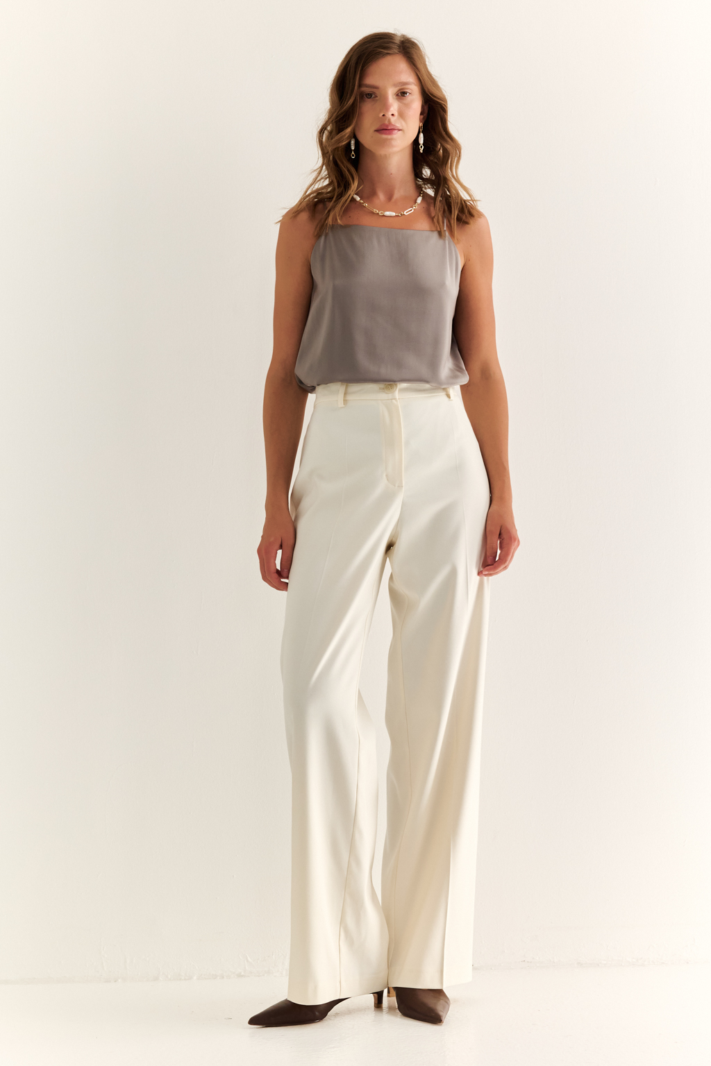 Прямые брюки: свобода, стиль, структура. Эти брюки с высокой посадкой и ровным силуэтом — воплощение современной женственности. Чёткие стрелки вытягивают силуэт, подчёркивая стройность ног, а широкие штанины добавляют образу лёгкости и статуса. Минималистичный дизайн с застёжкой на молнию и пуговицу, а также элегантный пояс делают модель идеальной для сочетания с жакетами, блузами или трикотажем. Идеальны как для офиса, так и для расслабленного городского образа. Современная классика, в которой сочетаются уверенность и комфорт.