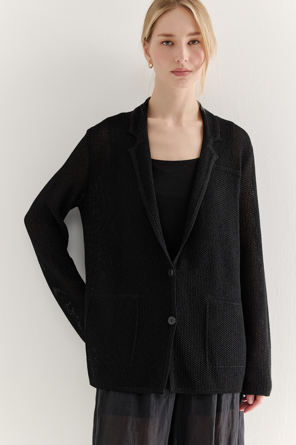 Жакет полуприлегающего силуэта черного цвета из вязаного трикотажа, в составе которого вискоза и хлопок. Плотная скрутка нити образует упругое, но в то же время дышащее полотно. Цельно вязаные лацканы элегантно переходят в воротник, обрамляя вырез. Прямые рукава полной длины завершают лаконичный силуэт. Этот жакет станет изысканным дополнением к непринужденному городскому образу.