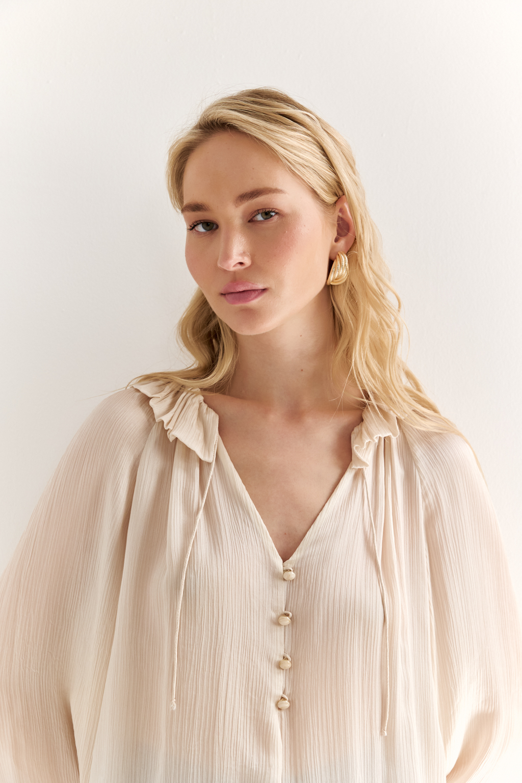 Блуза из 100% шёлка: воздушная элегантность с характером. Эта блуза создана из натурального шёлка — благородной ткани, которая буквально скользит по коже и придаёт образу утончённость. Объёмные рукава с  завязками создают лёгкий силуэт, а мягкая рюша по линии горловины добавляет динамики и изящества. Прямой крой обеспечивает комфорт и универсальность: блуза легко адаптируется под офисный стиль, романтичные образы или вечерние выходы. Носите с классическими брюками, юбками или джинсами — она всегда выглядит достойно. Чистый шёлк. Чистая элегантность.