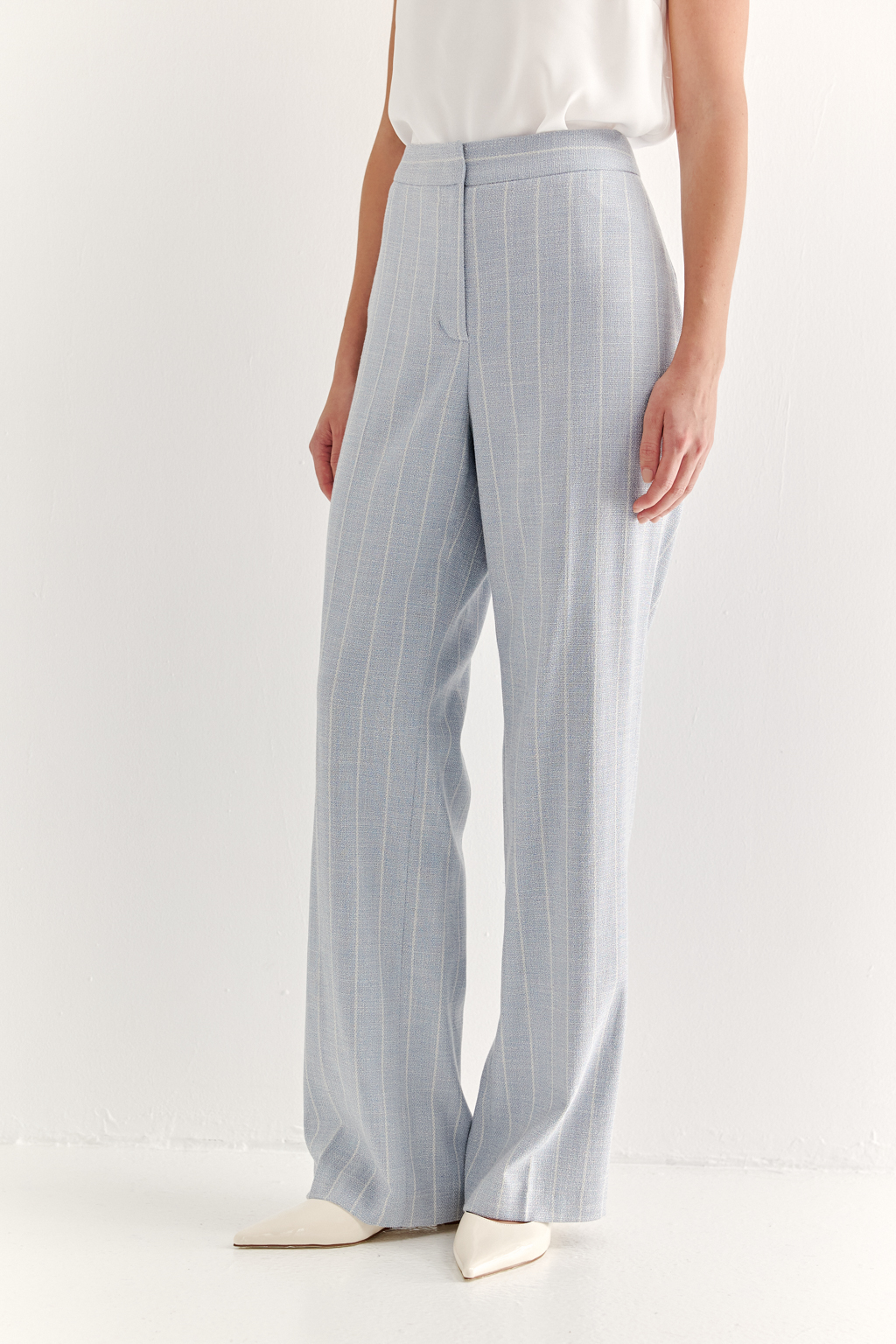 Эти брюки прямого силуэта созданы для абсолютного комфорта и расслабленной элегантности. Выполненные из ткани премиум-класса, они дарят невероятное ощущение мягкости, а нежный небесно-голубой оттенок эффектно подчеркнут светлой полоской в широком раппорте. Средняя посадка и удобные карманы делают их идеальными для любого типа фигуры. Ткань с оригинальным дизайном – эксклюзивная разработка бренда. Состав: хлопок, вискоза, эластан; за долговечность отвечает полиэстер. Брюки идеально дополнят городской look с жакетом архитектурного кроя их этой же ткани, создавая модный многослойный образ.