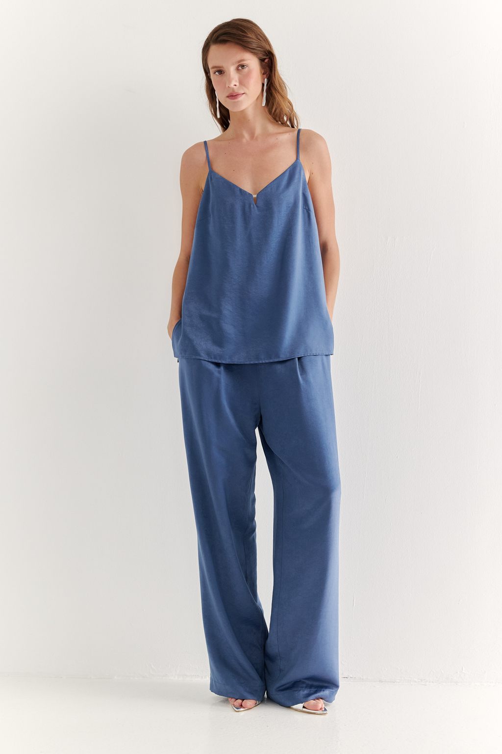 Топ из струящегося атласа с крэш эффектом в цвете деним. Топ на регулируемых бретелях свободного кроя с декором на линии декольте.