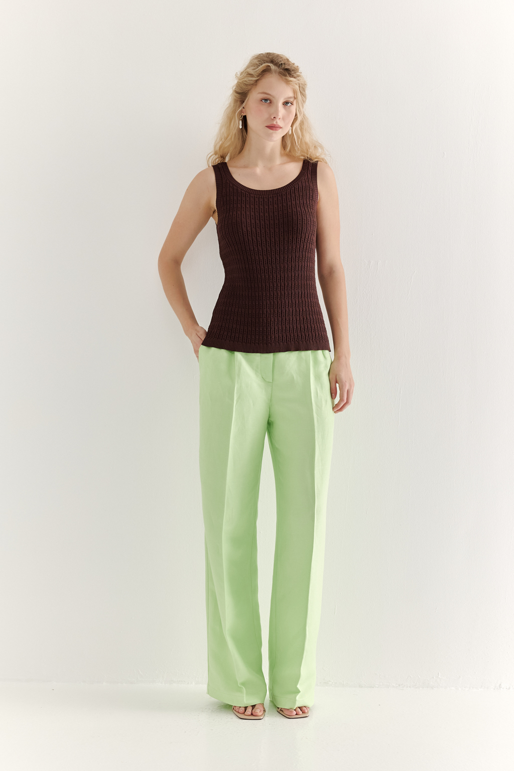 Фактурный топ-майка прилегающего силуэта из вискозной пряжи связана косами, проймы и горловина отделаны вязанными кантами. Цвет – шоколадно-коричневый.