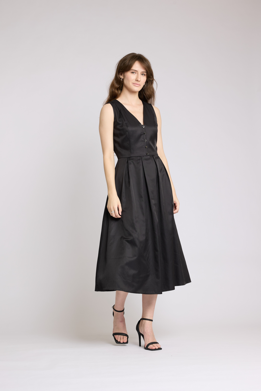 Платье длины миди с V-образным вырезом с декоративными пуговицами. Юбка пышная со складками. По бокам карманы.