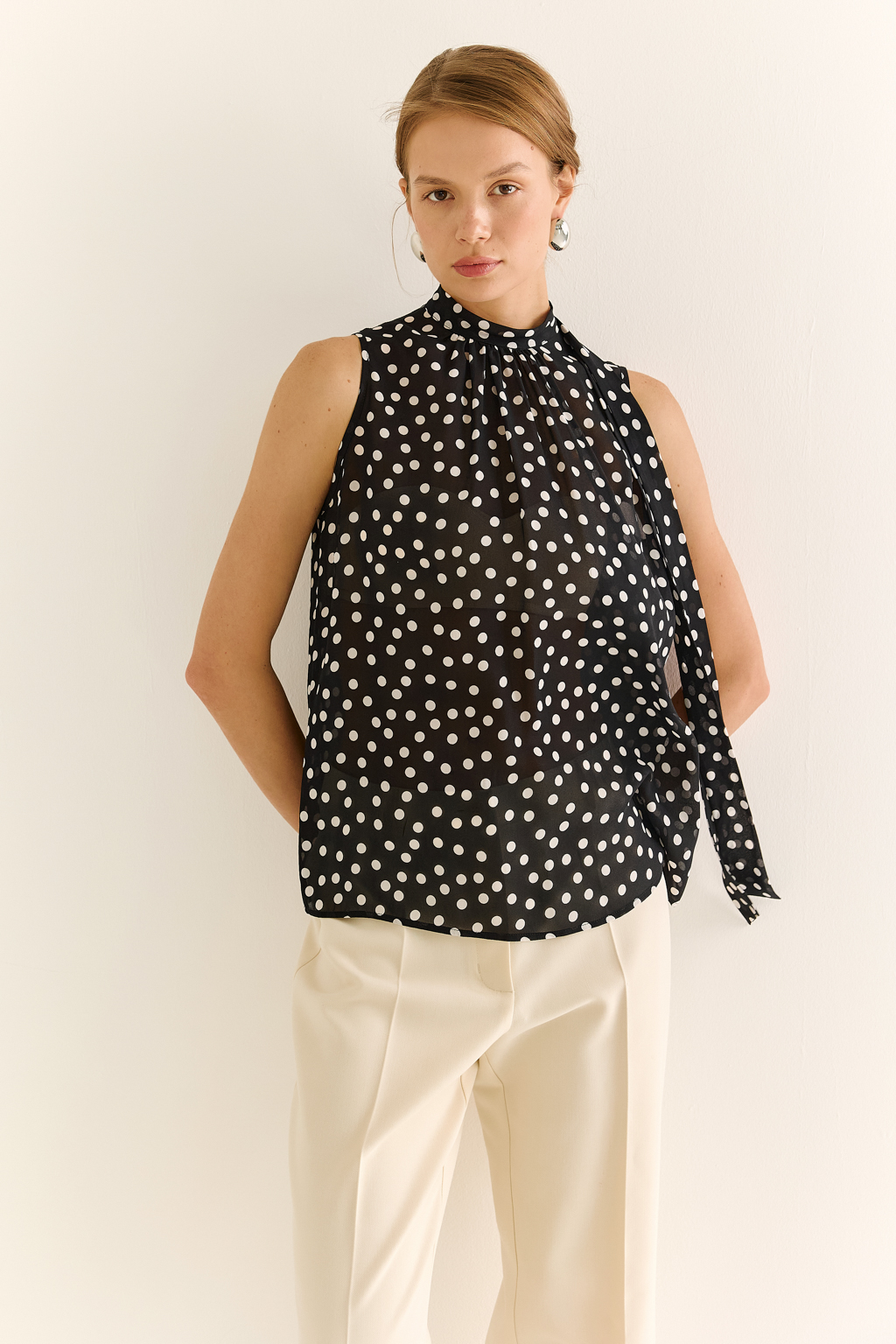 Блузка с бантом: женственность и утончённый акцент. Эта блузка без рукавов — воплощение элегантной простоты с выразительной деталью. Горловина украшена мягким бантом, который добавляет образу нотки утончённости и романтичного шика. Лёгкая драпировка спереди делает силуэт свободным, но изящным, подчёркивая вкус и стиль. Идеальна для офисных будней, деловых встреч или вечерних образов. Эффектно смотрится под жакет или кардиган, но и сама по себе становится акцентом. Сила — в деталях. Женственность — в каждом движении.